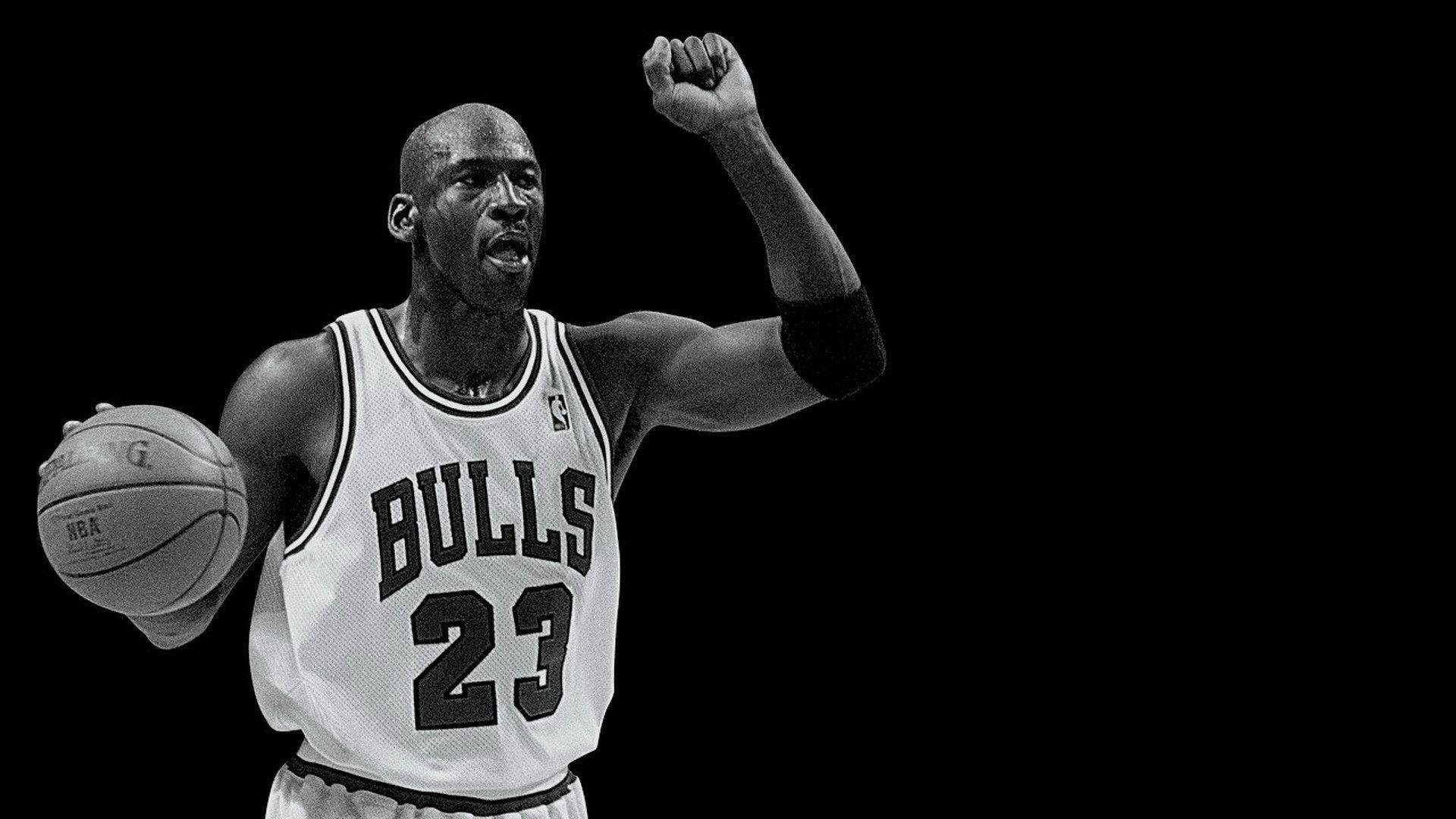 Black and white photo of Michael Jordan, number 23 of the Chicago Bulls, holding a basketball and raising his fist in celebration