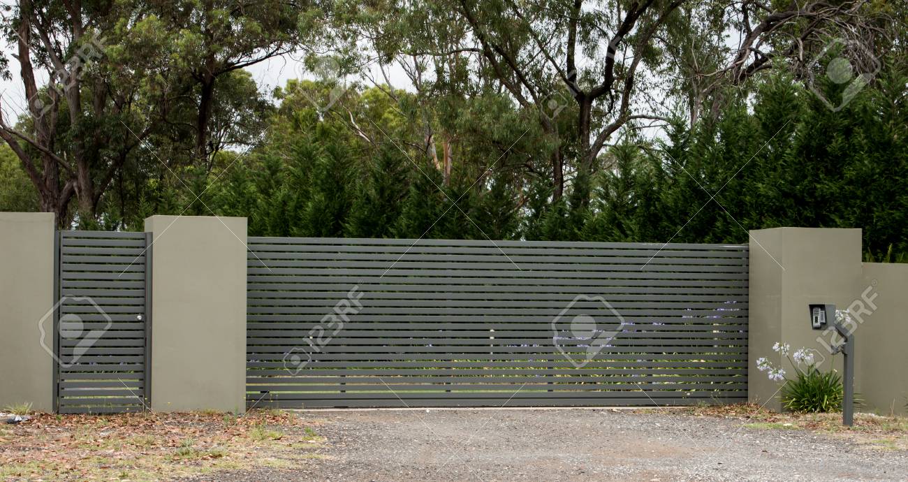 Metal Driveway Entrance Gates Set In Brick Fence Leading To Rural