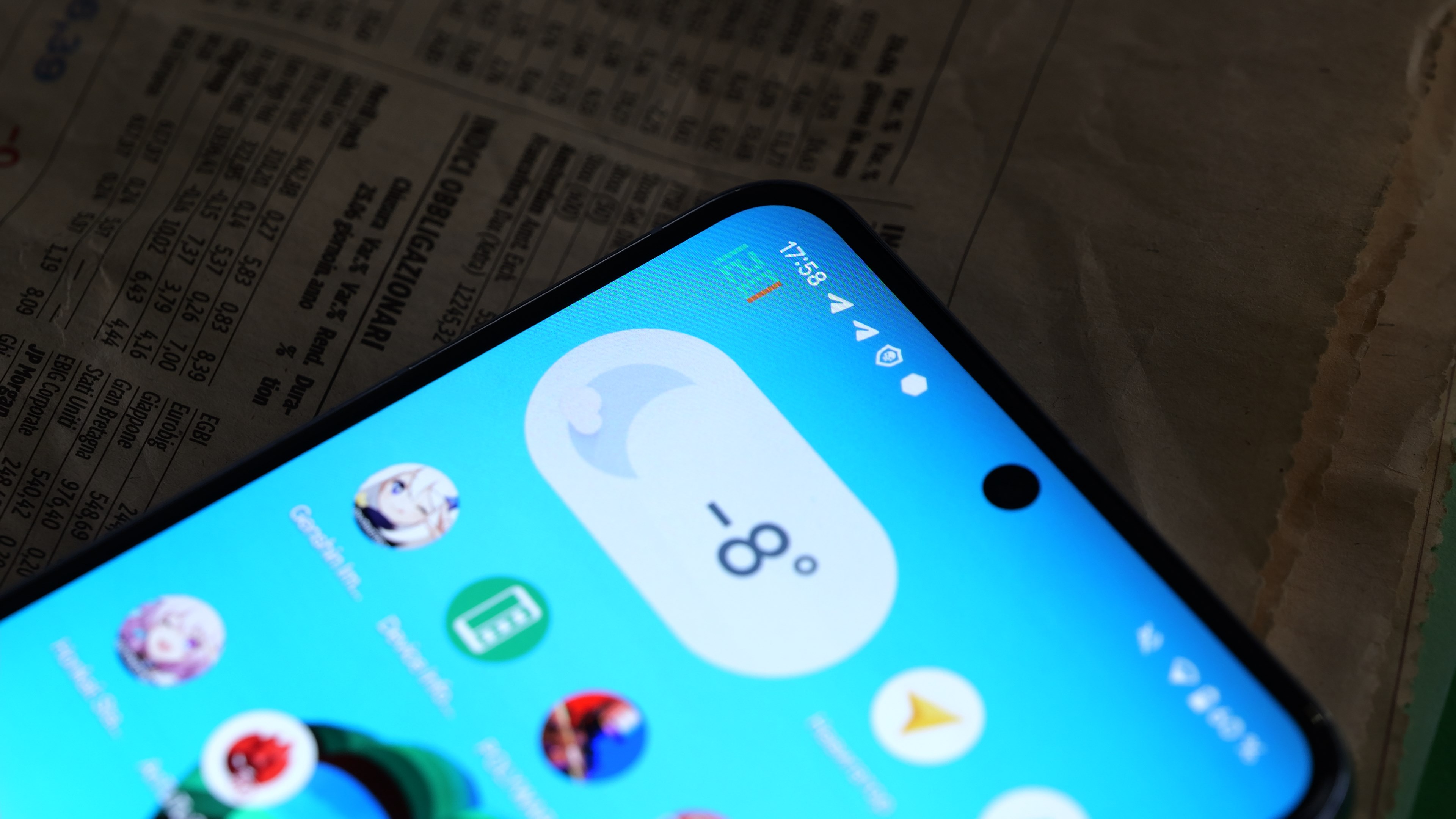 Close-up of a smartphone displaying a weather widget showing -8 degrees Celsius and various app icons, overlaid on a financial newspaper