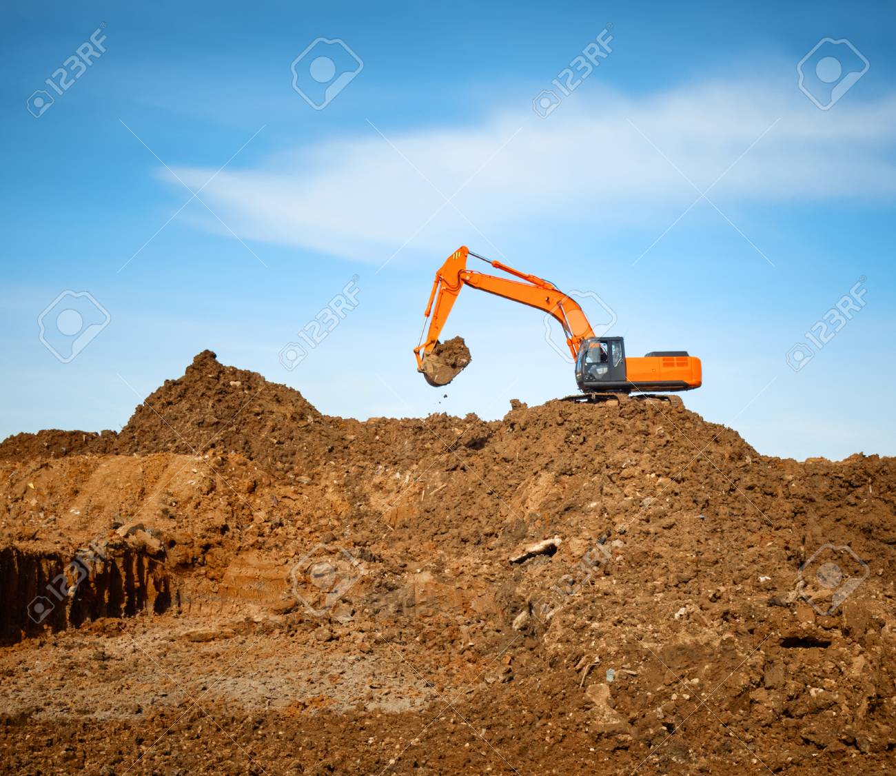 Excavator Digs The Earth On A Background Of Blue Sky Stock Photo
