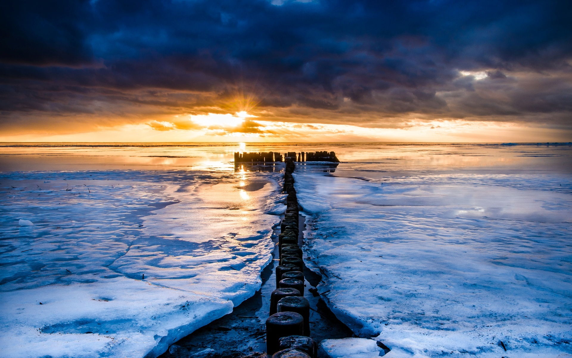 Frozen sea at sunset with wooden breakwaters