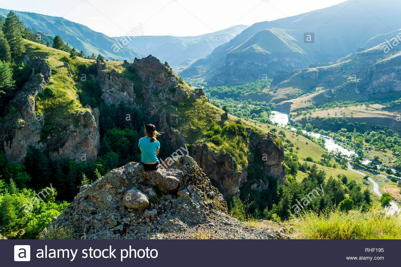 Girl Sitting On A Rock Looking At The Against Background