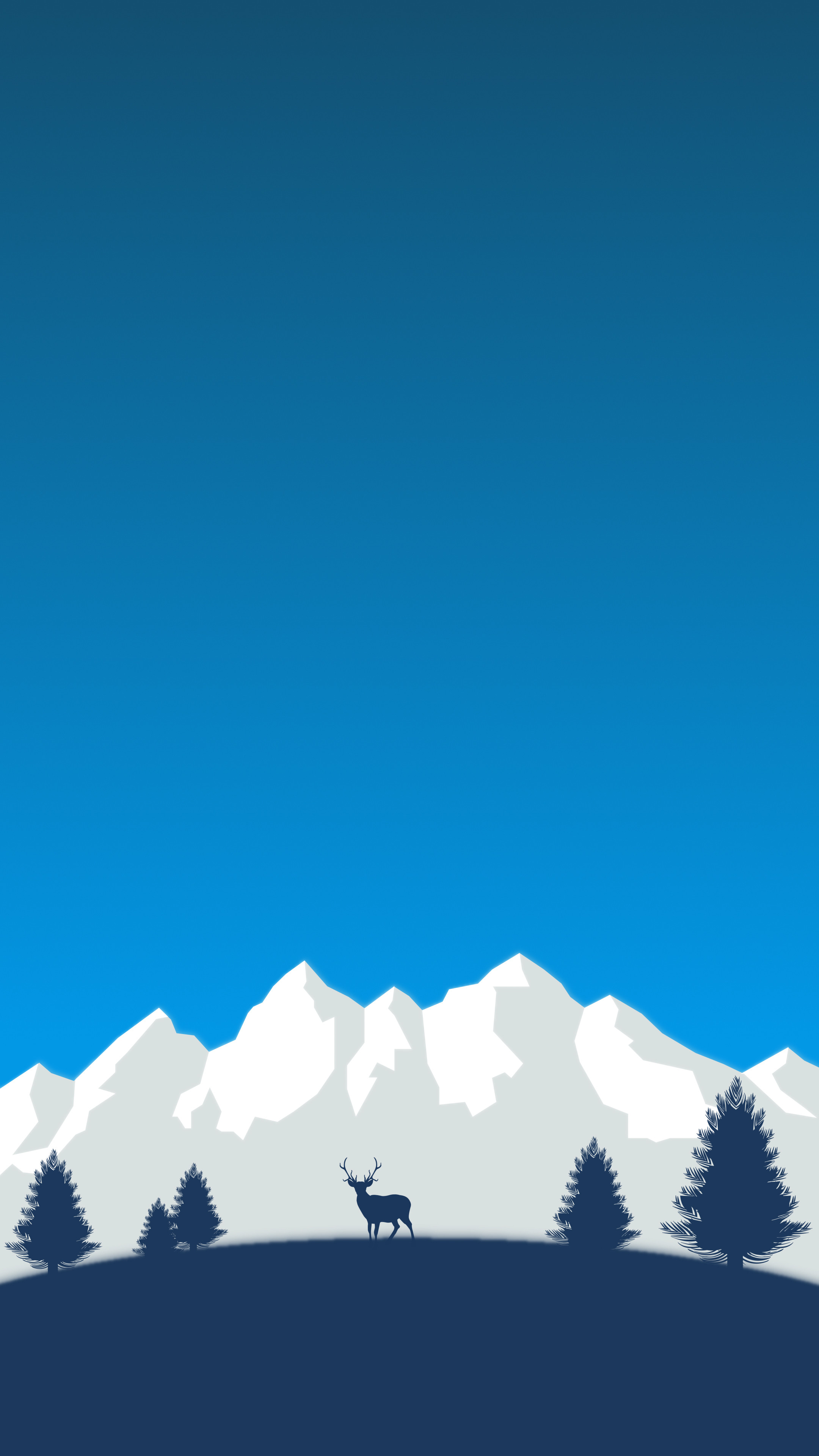 Silhouette of a deer standing in a field with snowy mountains in the background under a clear blue sky