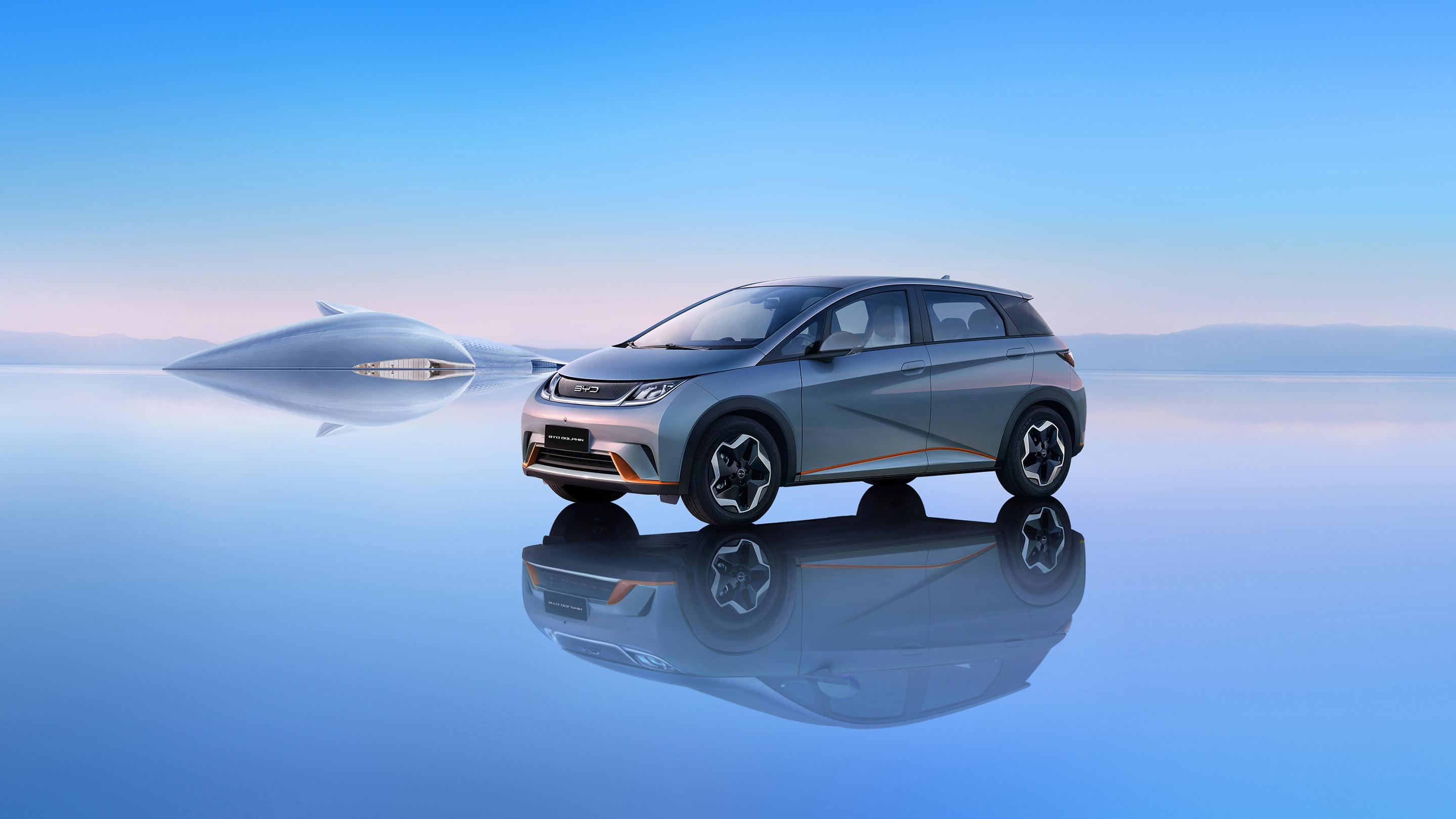 A futuristic BYD Shark electric car parked on a serene, reflective surface with a futuristic vessel in the background, highlighting its sleek design and innovative technology