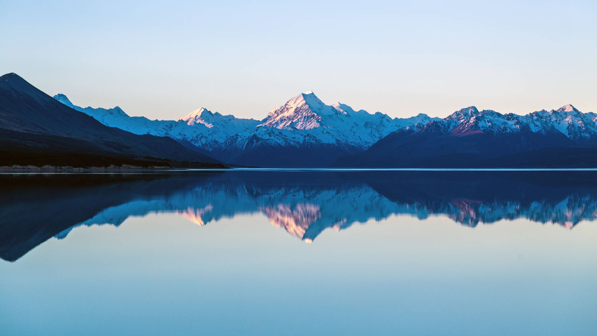 A breathtaking 4K wallpaper featuring a serene lake reflecting snow-capped mountains, perfect for a MacBook Pro