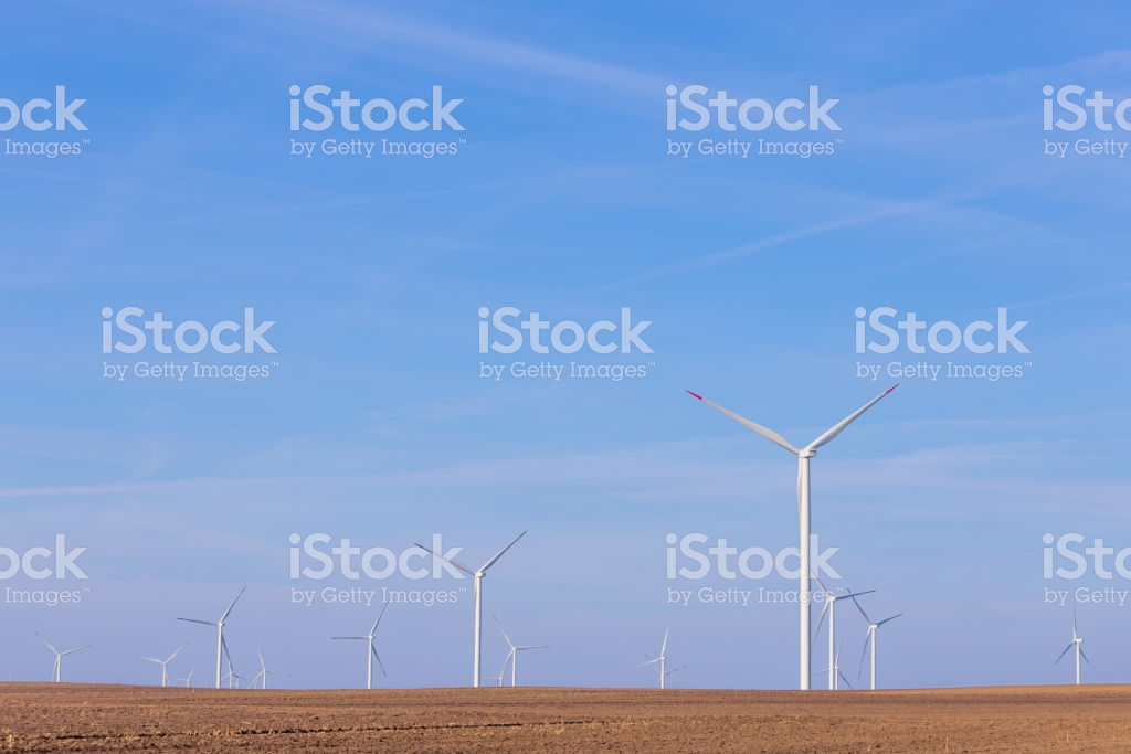 Windmill Turbines On Agricultural Field With Blue Sky In