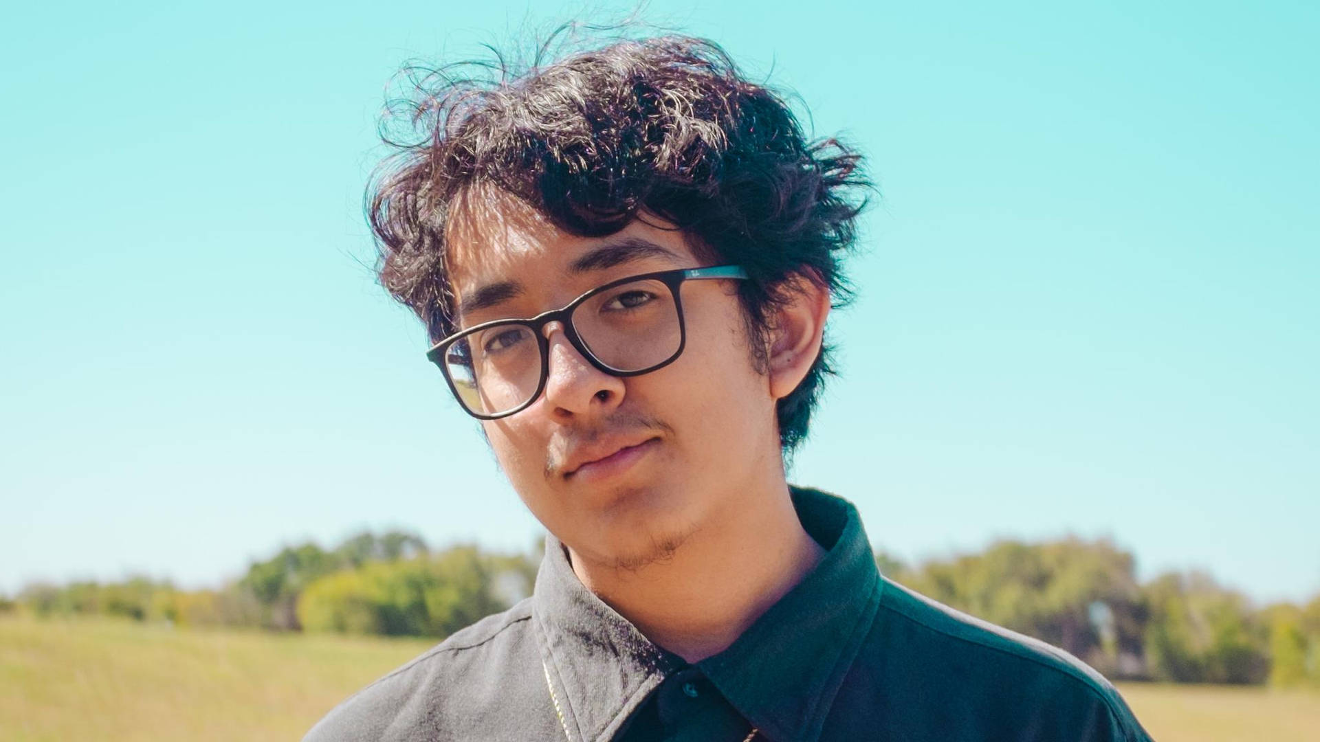 Cuco With His Black Shirt And Eyeglasses Wallpaper