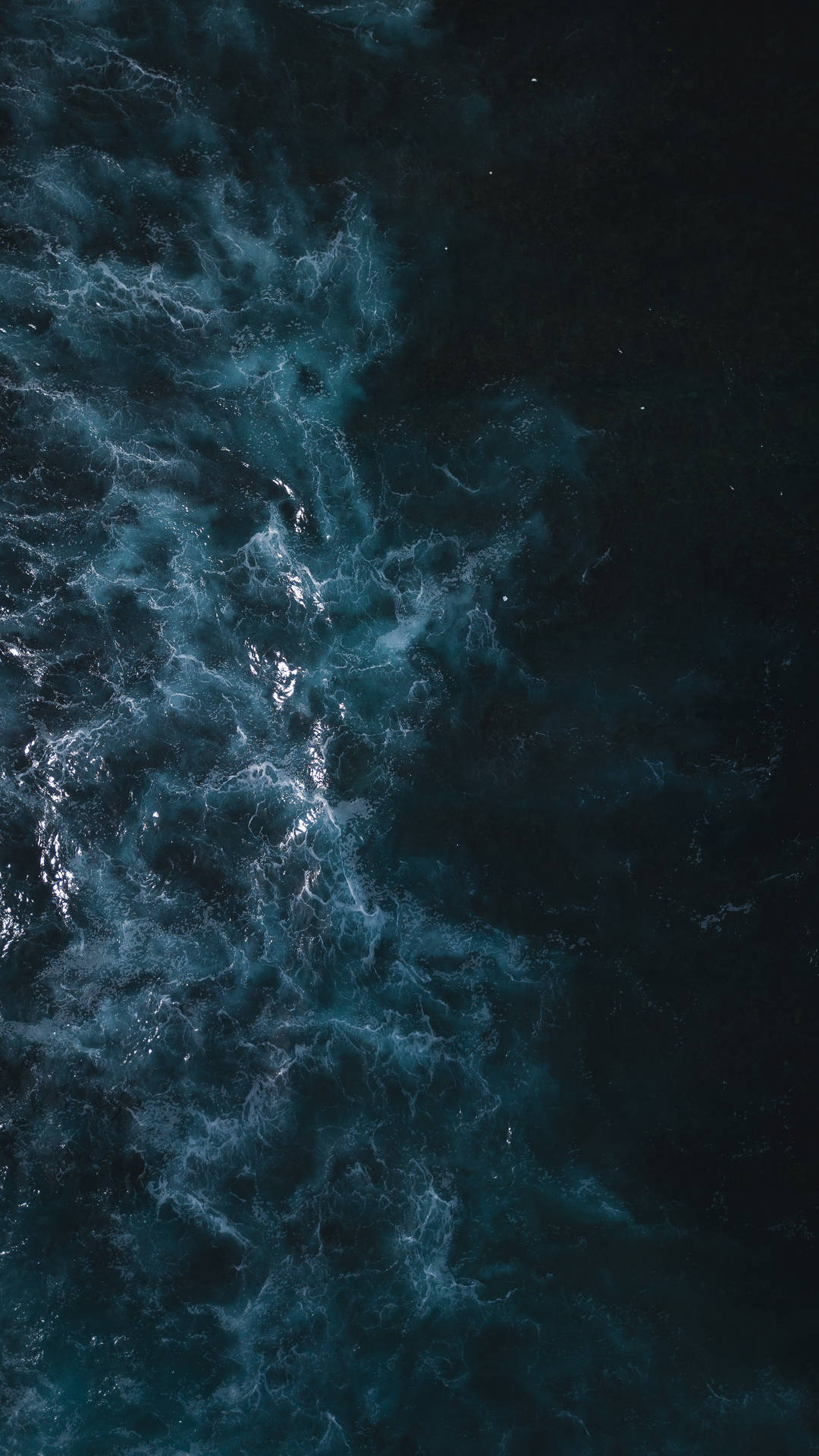 Dark navy blue ocean waves crashing, creating a textured and moody seascape