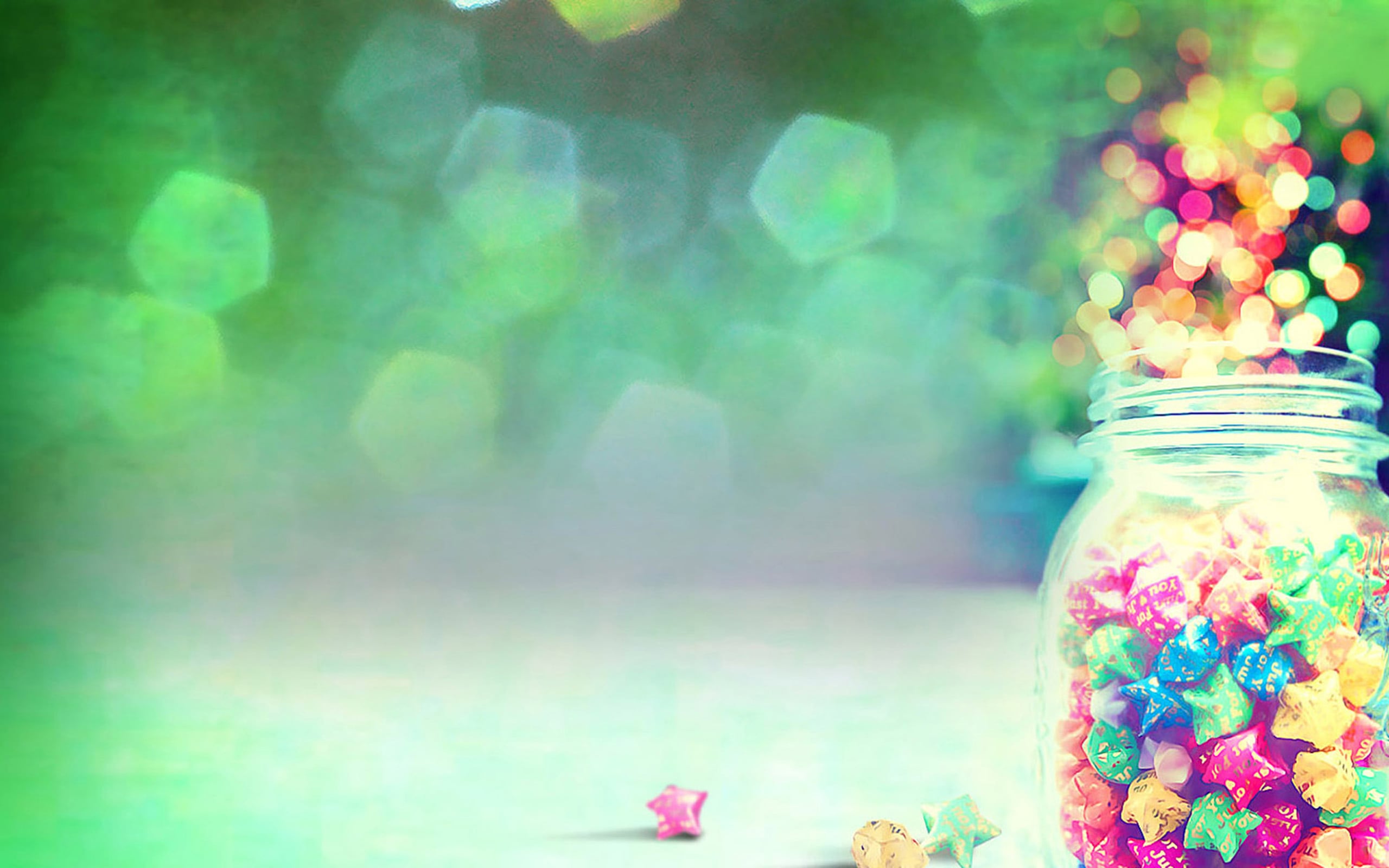 Colorful origami stars in a jar against a bokeh background, perfect for a cute laptop wallpaper