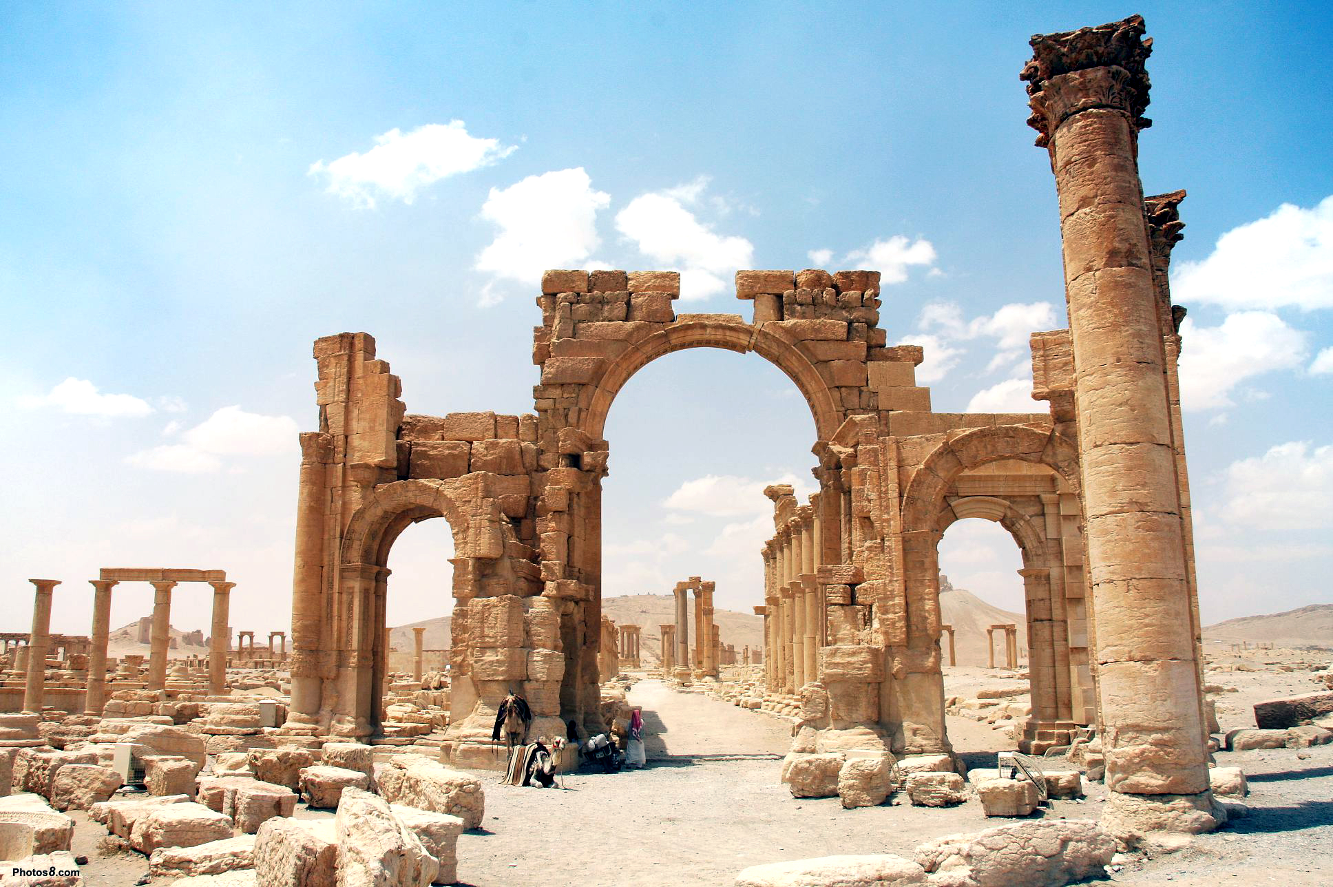 Ancient ruins of Palmyra, Syria, with a large arch and colonnade, under a clear blue sky