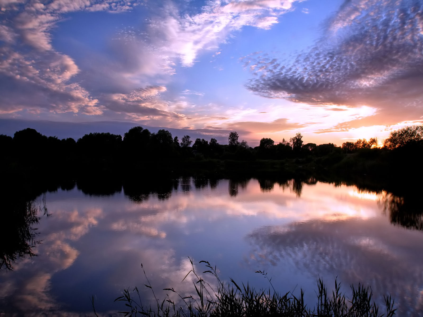 A serene sunset reflected in a calm lake, creating a picturesque wallpaper for computer