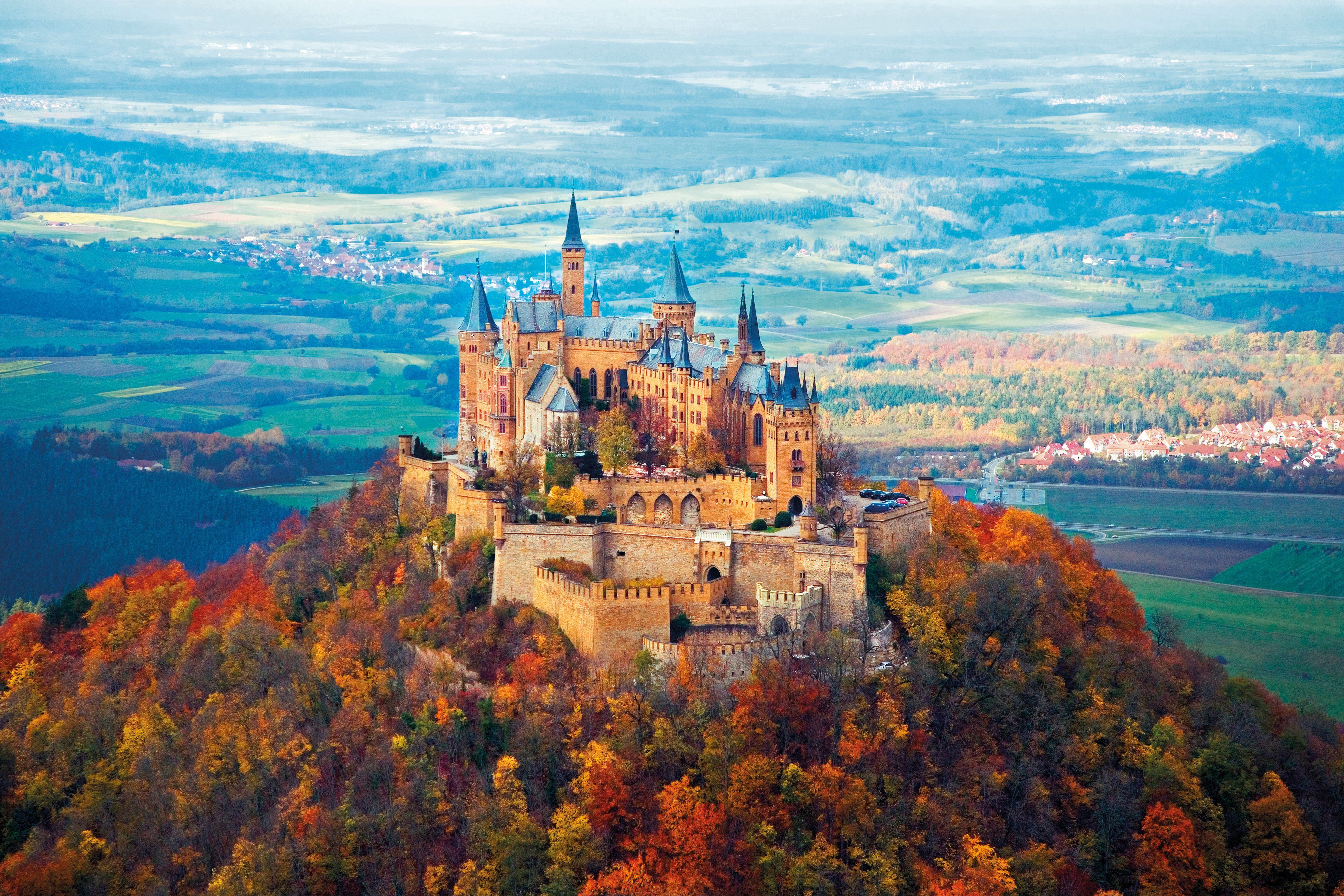 Majestic castle perched on a hilltop amidst colorful autumn foliage