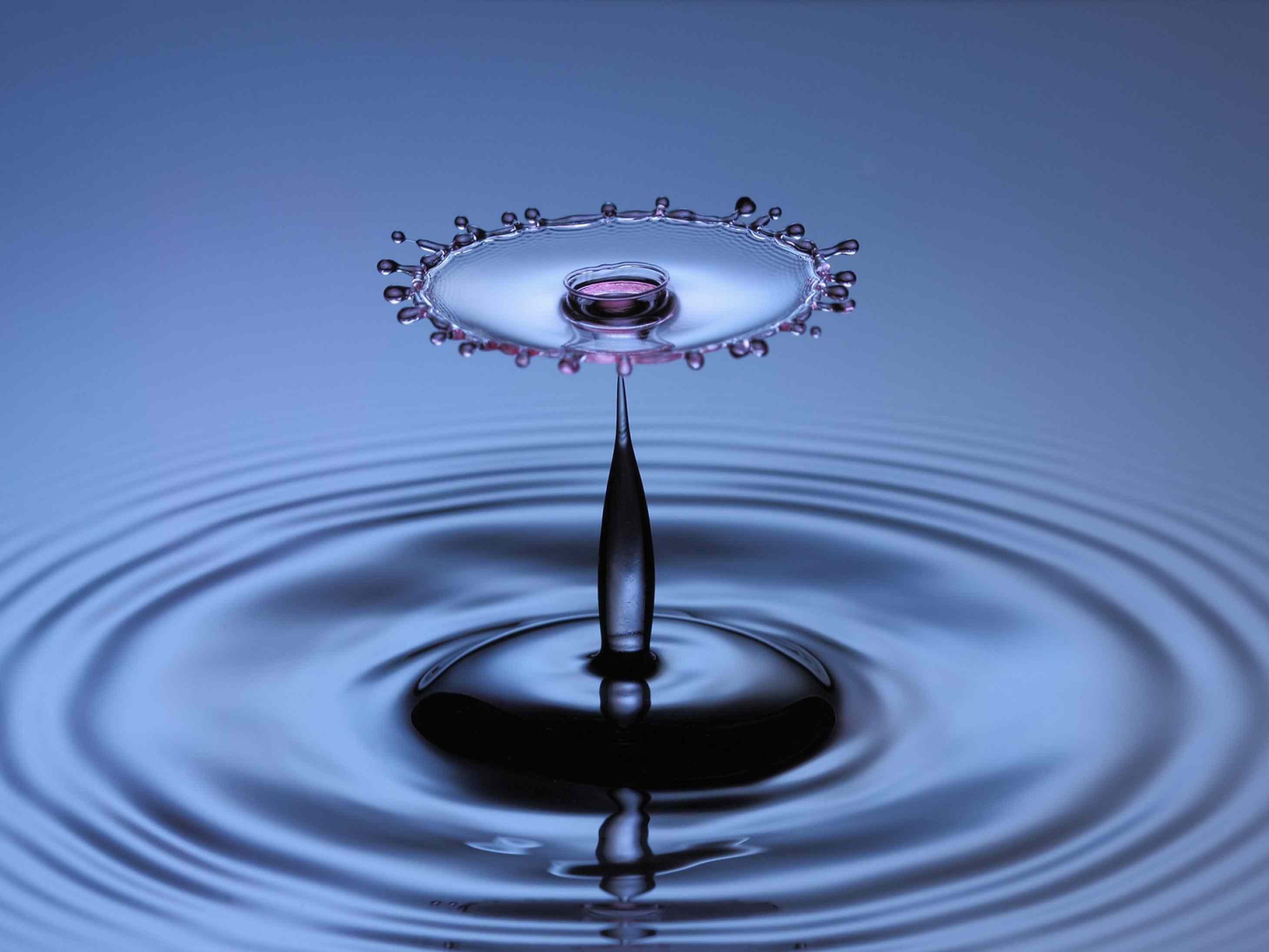 A mesmerizing macro photograph of a water droplet collision, creating a crown-like splash above a central column of water