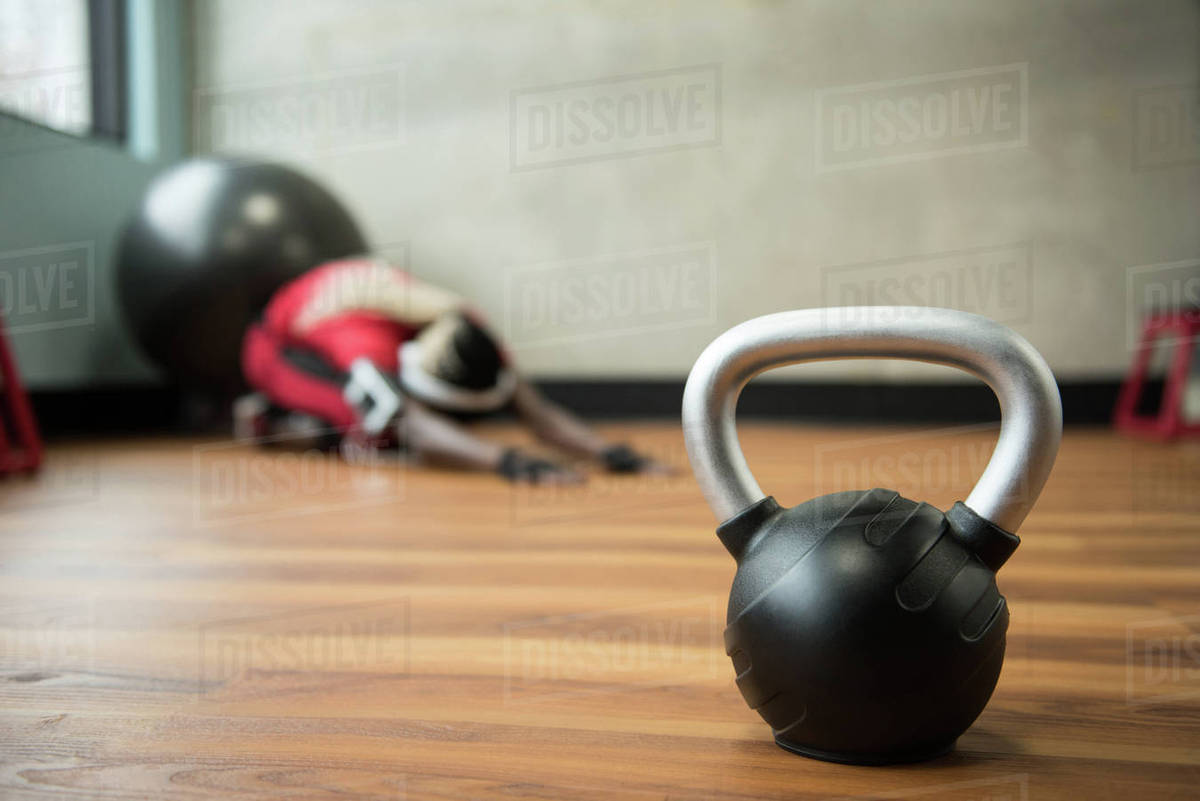 Kettlebell On A Wooden Floor While Fit Woman Exercising In The