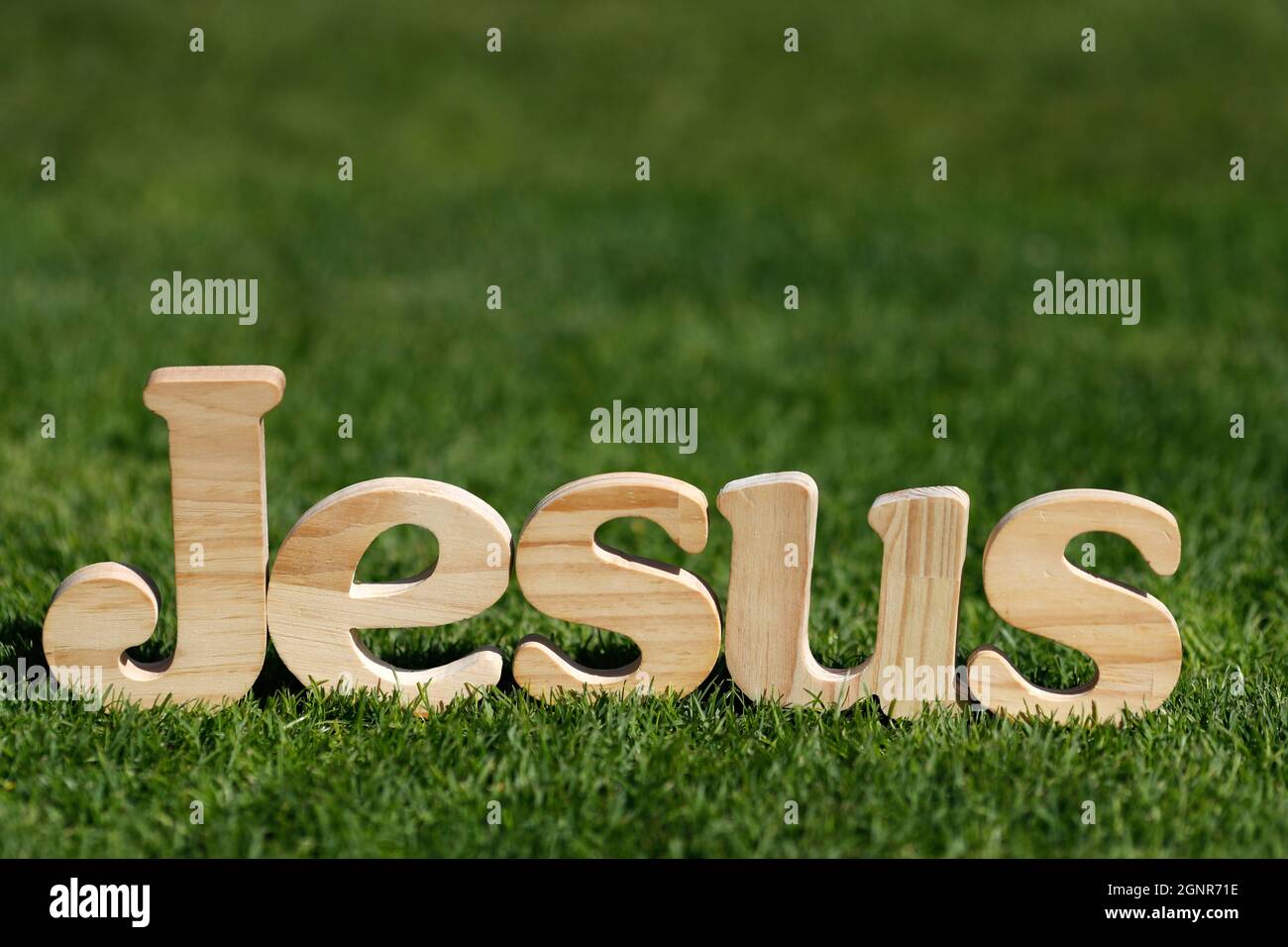Wooden Letters Forming The Word Jesus On A Background Of Green