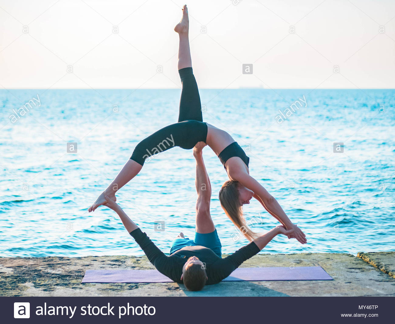 Young Beautiful Couple Practicing Acro Yoga On The Sea Beach Near