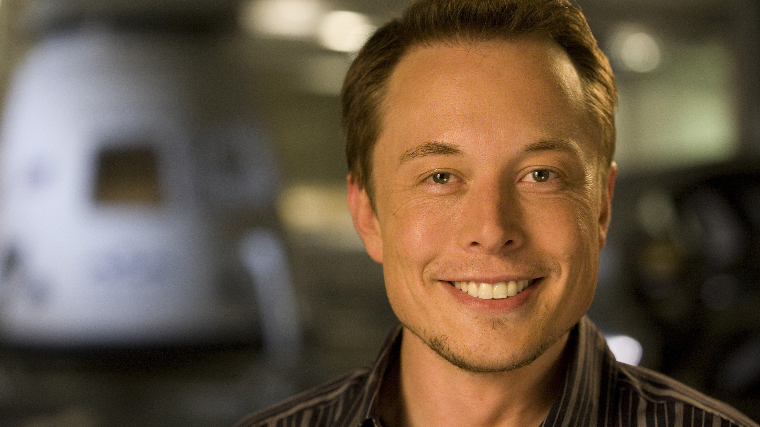Close-up portrait of Elon Musk smiling, with a blurred background
