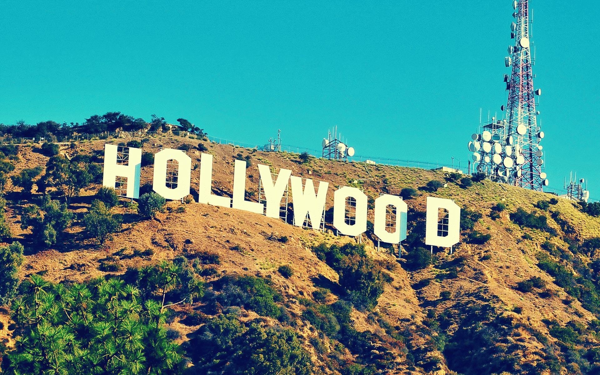 The iconic Hollywood Sign standing tall against a clear blue sky on Mount Lee, a symbol of the entertainment industry and the American Dream