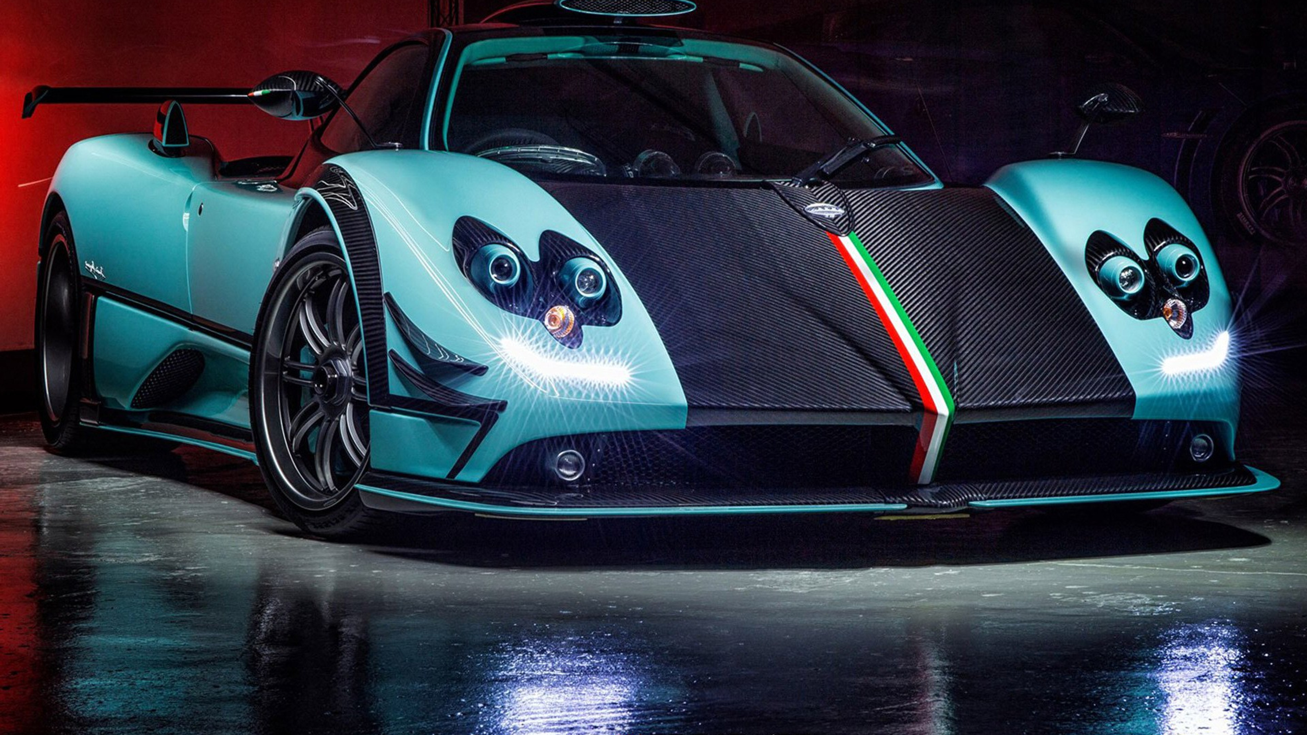 A stunning Pagani Huayra, finished in a unique turquoise and black color scheme, with the iconic Italian flag stripe running down the center, parked in a dimly lit garage, its headlights glowing brightly, reflecting off the polished floor