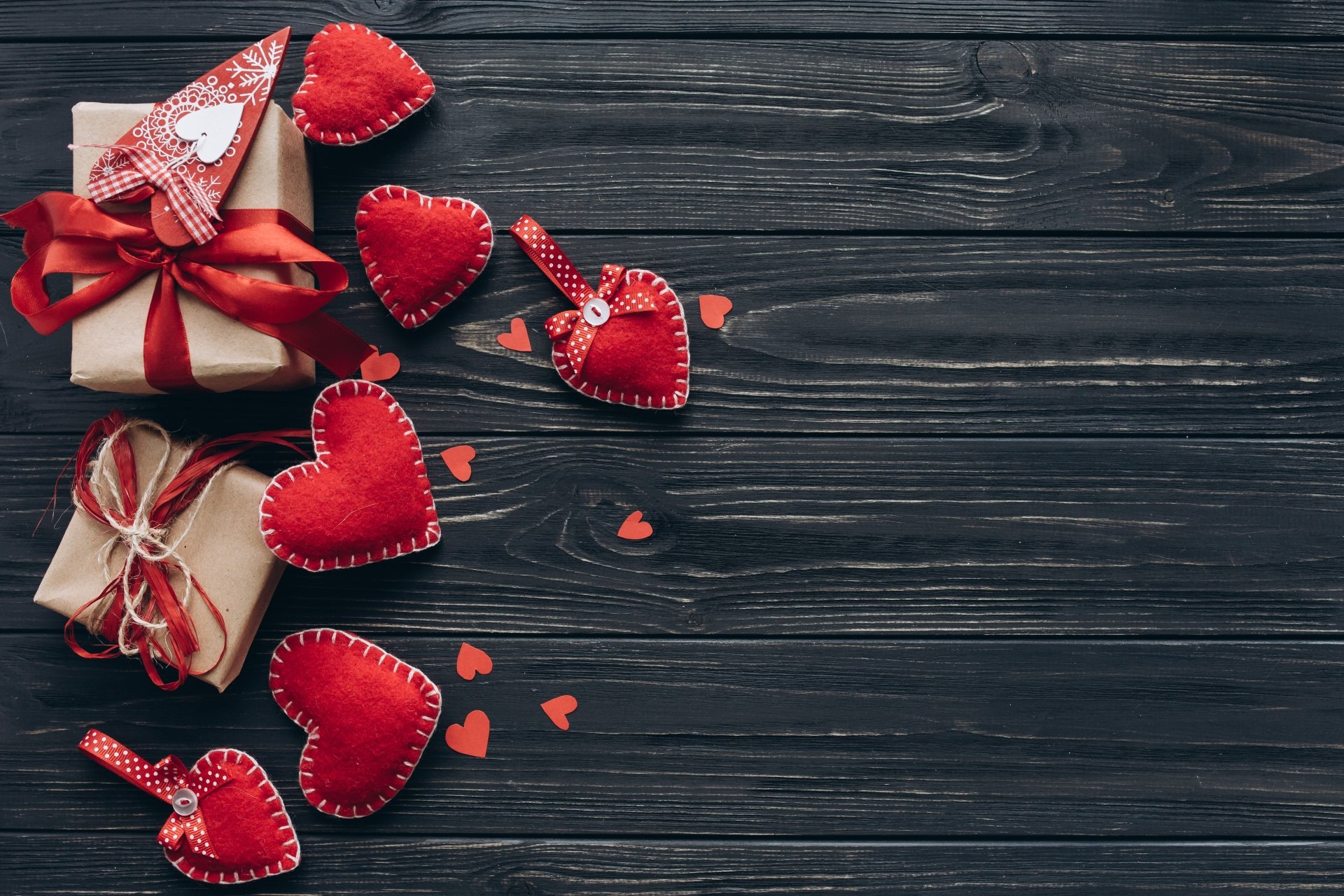 Rustic Valentine's Day background with handmade hearts and gifts on dark wooden planks