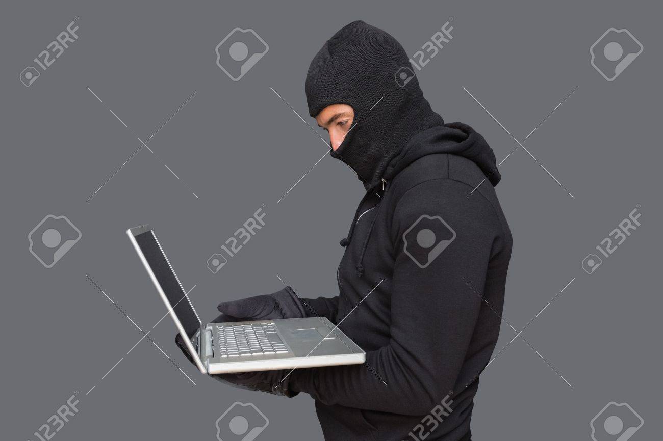 Hacker Using Laptop To Steal Identity On Shadowy Background Stock