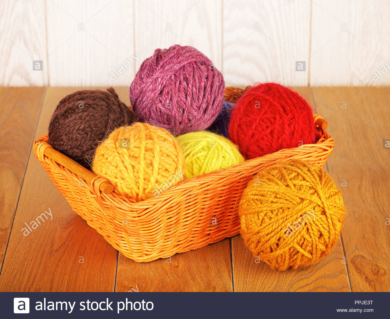 Colorful Yarn Balls In Wicker Basket On Wooden Background Stock