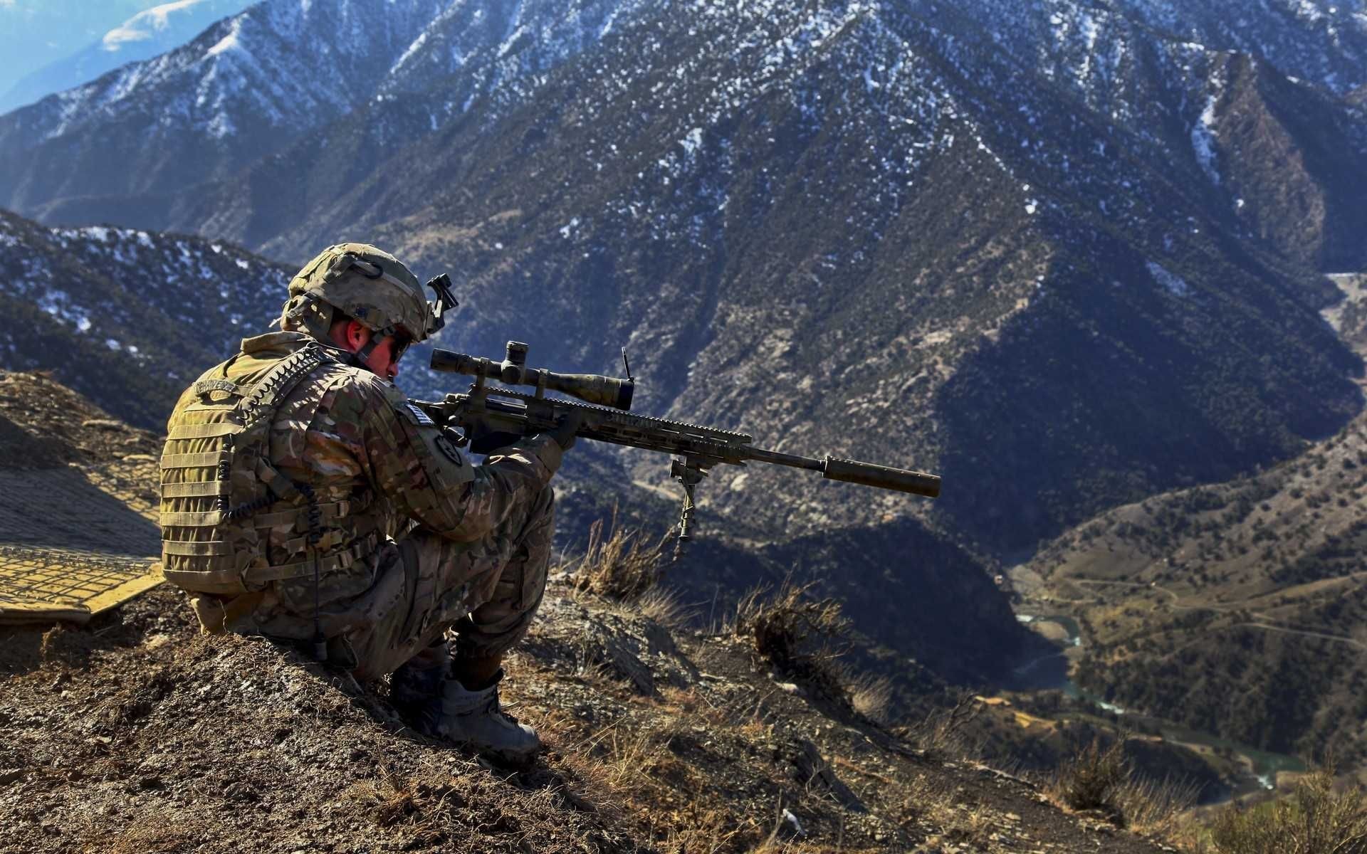 A soldier perched on a mountain ridge, aiming a sniper rifle, with a backdrop of rugged, snow-capped mountains