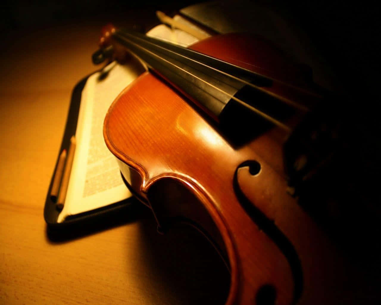 A Violin Is Sitting On Table With An Open Book Wallpaper