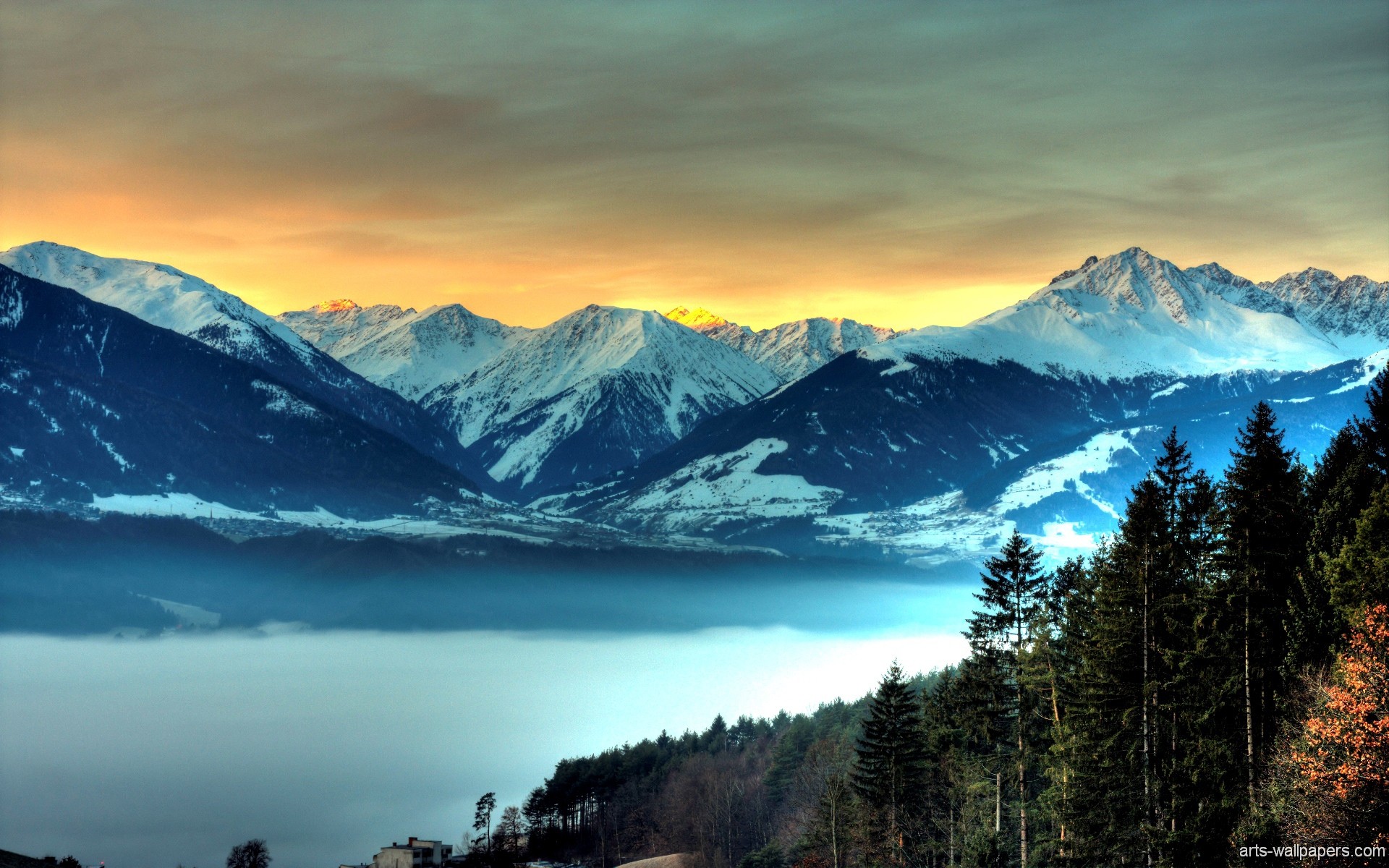 Sunrise over snow-capped mountains and a valley filled with fog