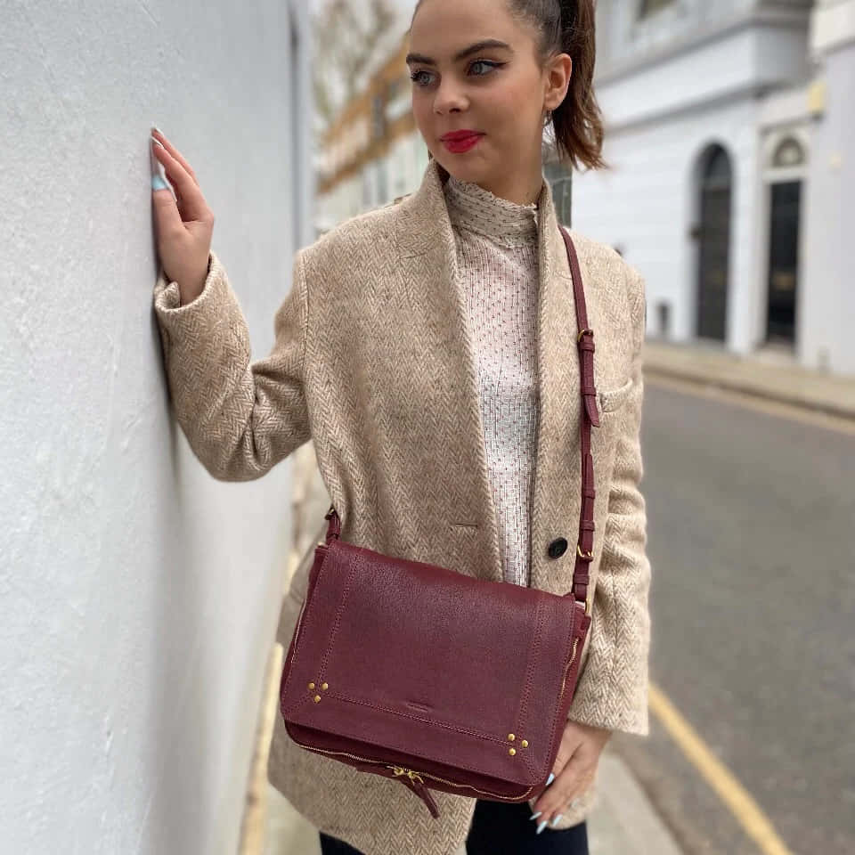 Chic Woman Flaunting Her J R Me Dreyfuss Igor Bag On The Wallpaper