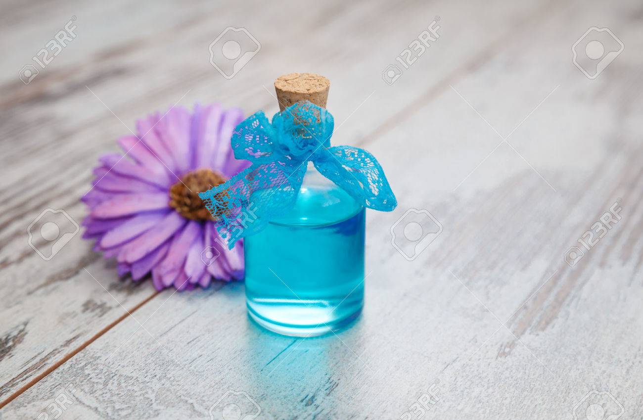 Blue Cologne In Small Bottle And Dry Flower On Old Tree Background