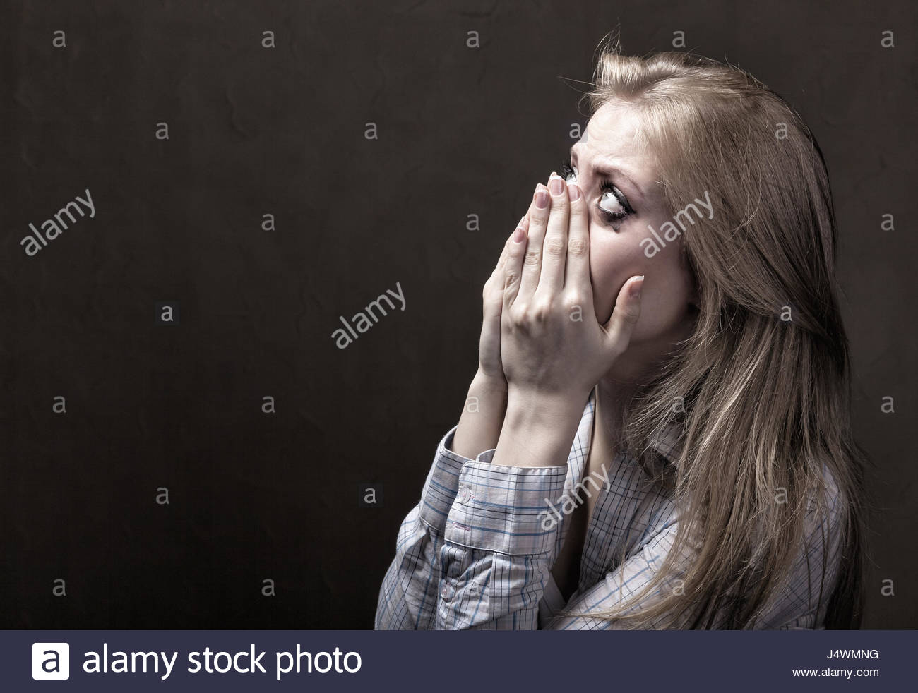 Young Woman Desperately Crying On A Dark Background Stock Photo