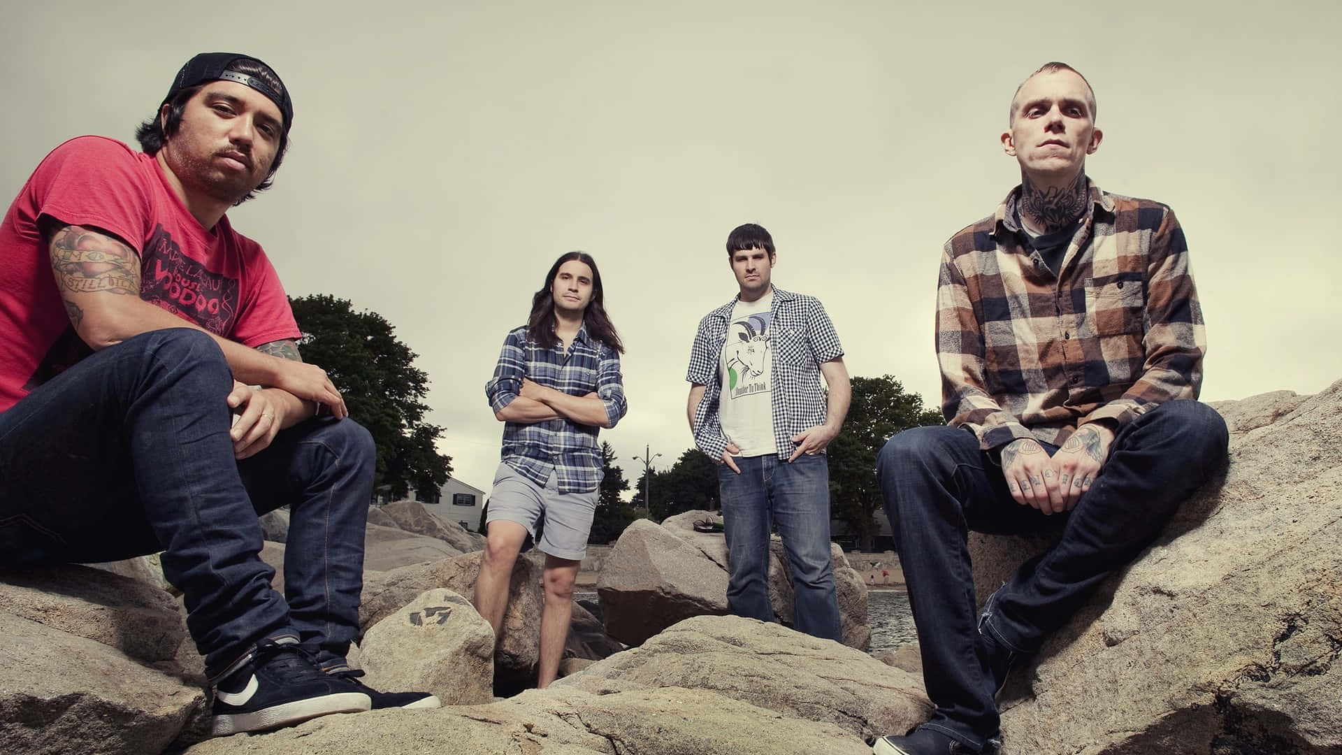 A band of four members posing on rocks near a body of water