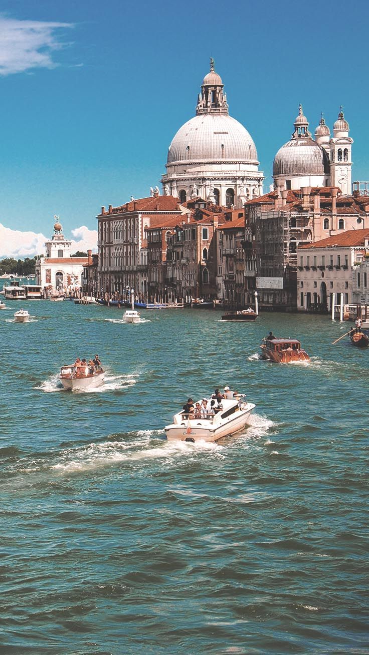 Several Boats Are Traveling Down The Water In Front Of Buildings And Wallpaper