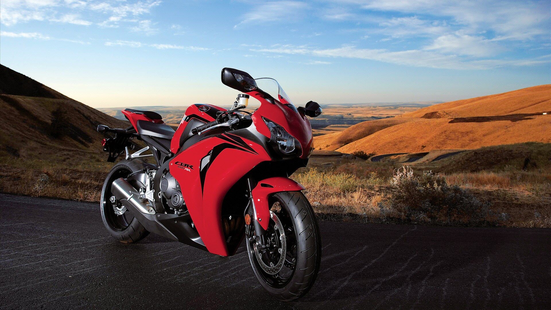 Red Honda CBR sportbike parked on a scenic mountain road at sunset