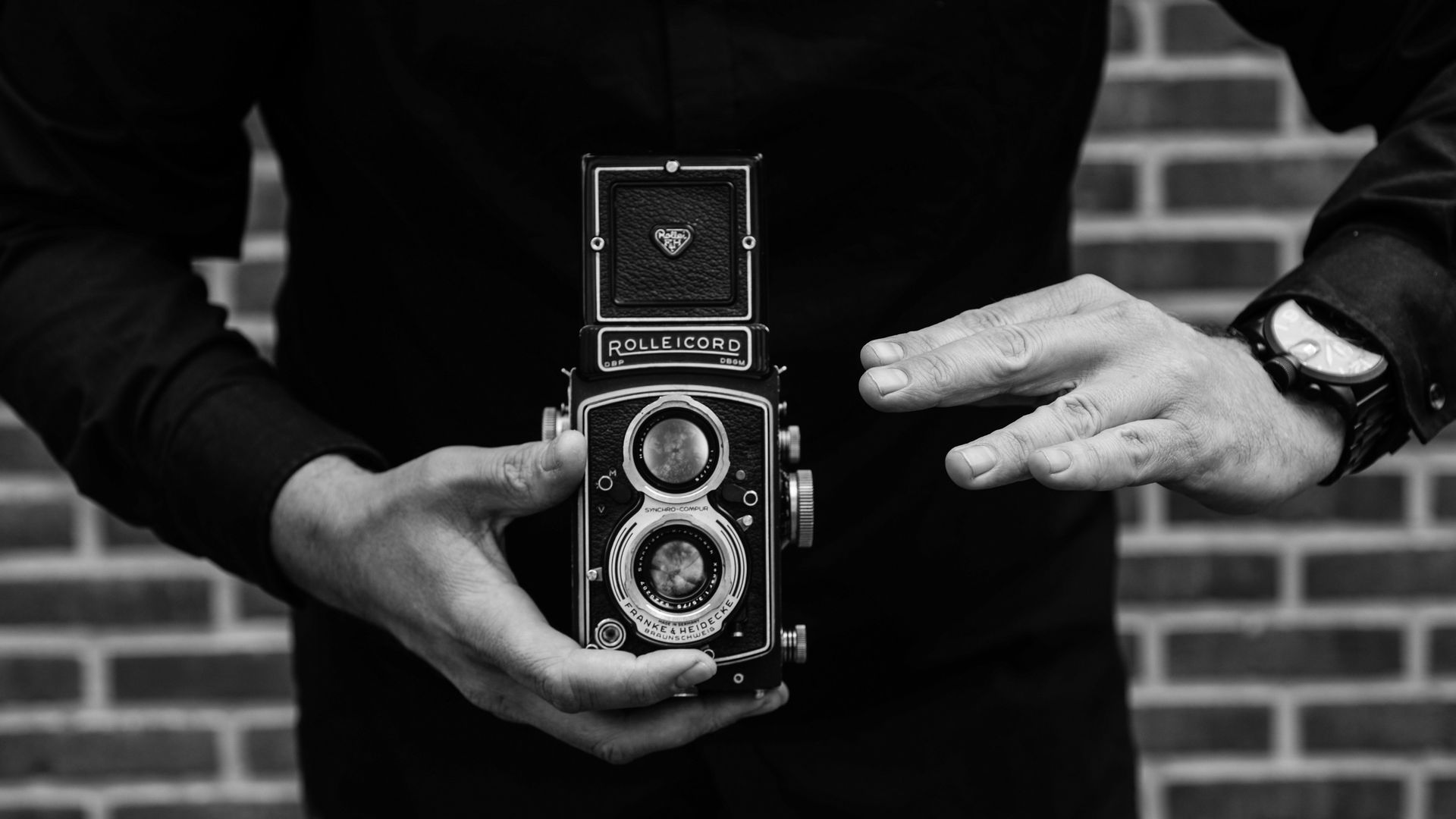 Grayscale Photo Of Man Holding Rolleicord Camera Wallpaper