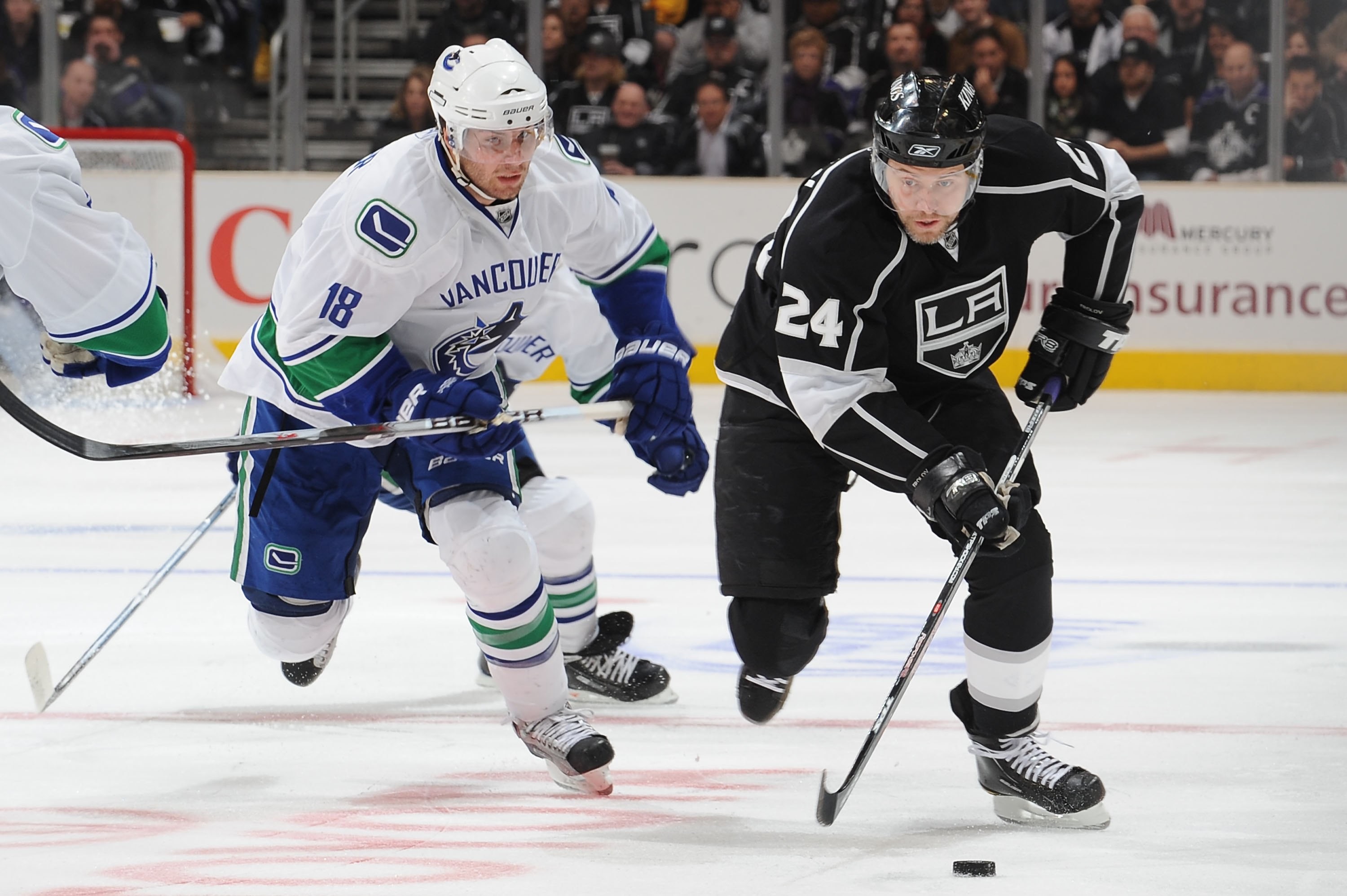 Two hockey players from opposing teams face off during a fast-paced NHL game