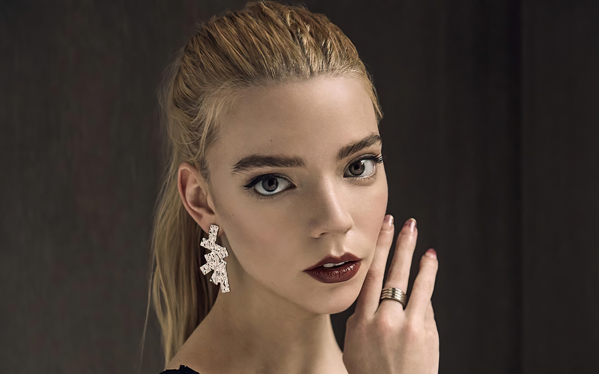 Close-up portrait of Anya Taylor-Joy with her hand touching her face