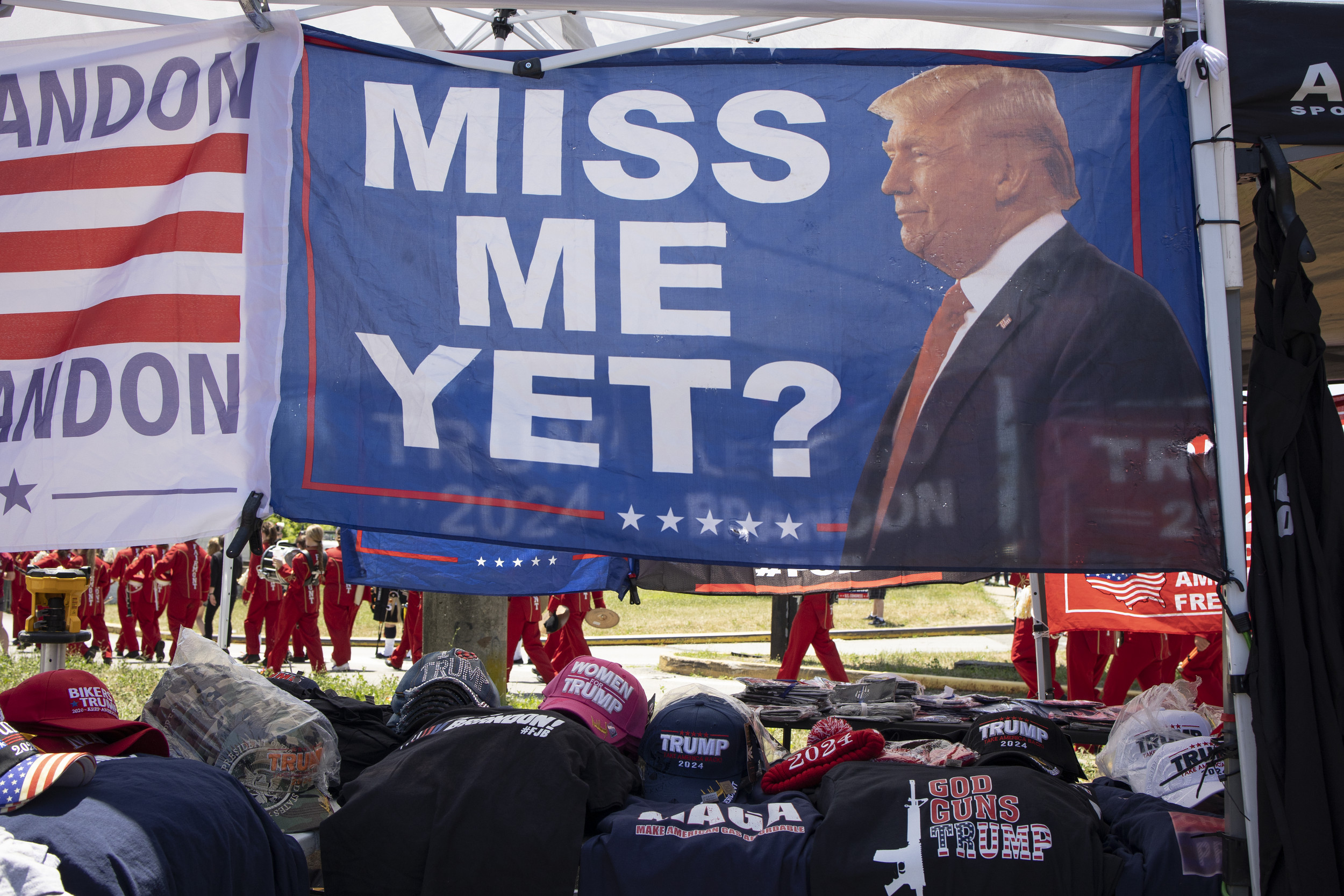 A banner at a pro-Trump rally displays the text 'Miss Me Yet?' with a picture of Donald Trump and '2024' below it, suggesting support for his 2024 presidential campaign