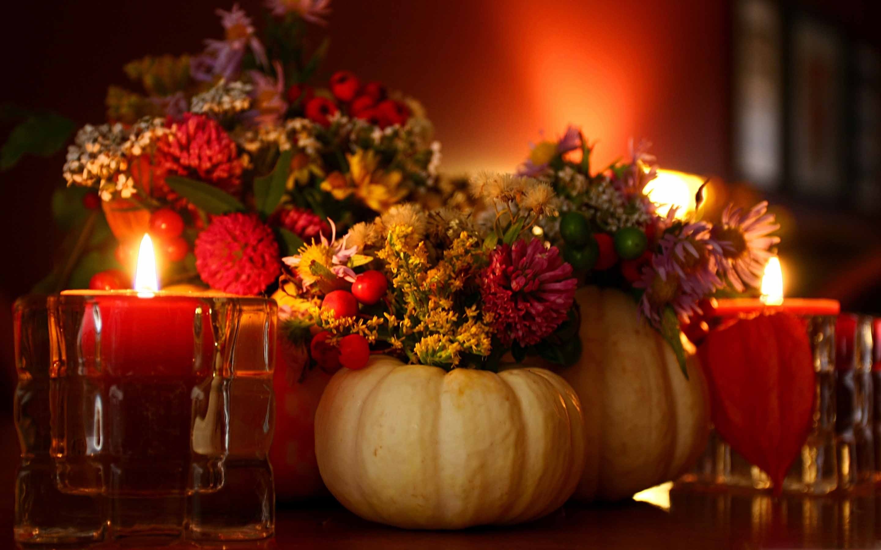 A warm and inviting Thanksgiving still life with white pumpkins adorned with colorful flowers and glowing red candles