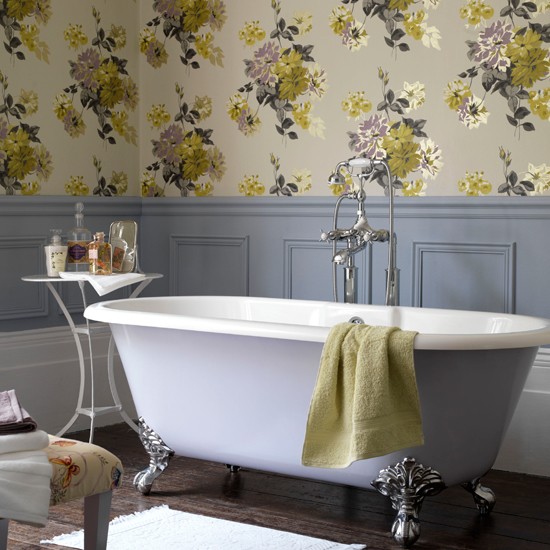 Freestanding purple bath with grey painted walls and floral wallpaper