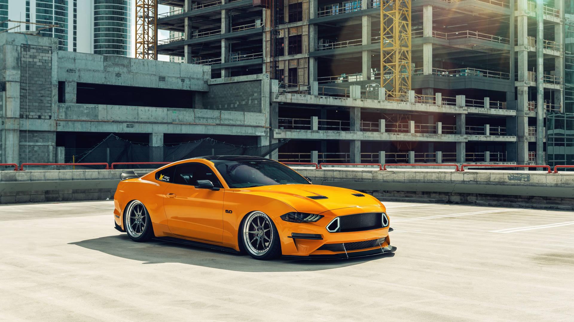 A Yellow Ford Mustang Parked In Front Of Building