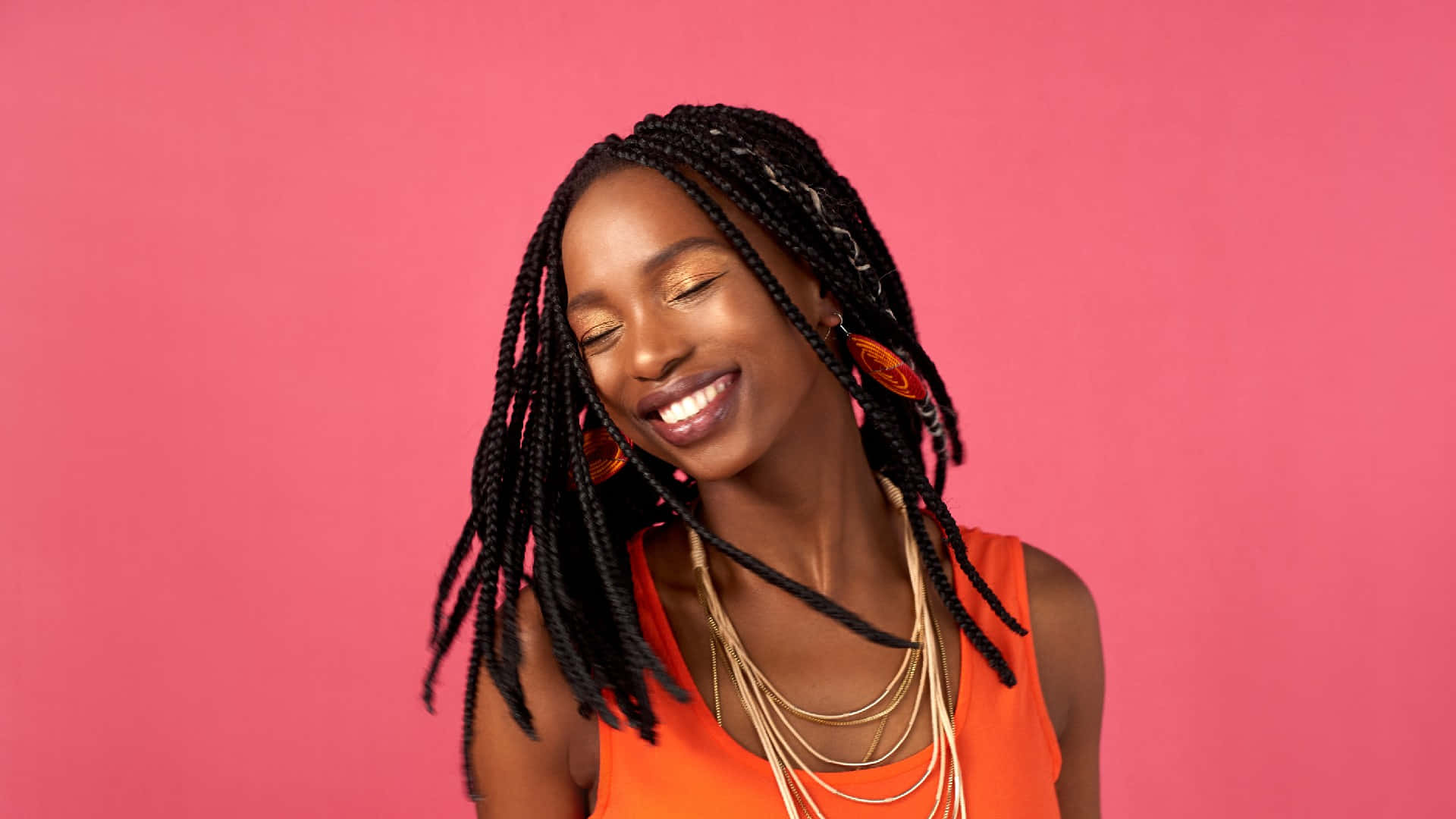 A Young Woman With Braids Smiling On Pink Background Wallpaper