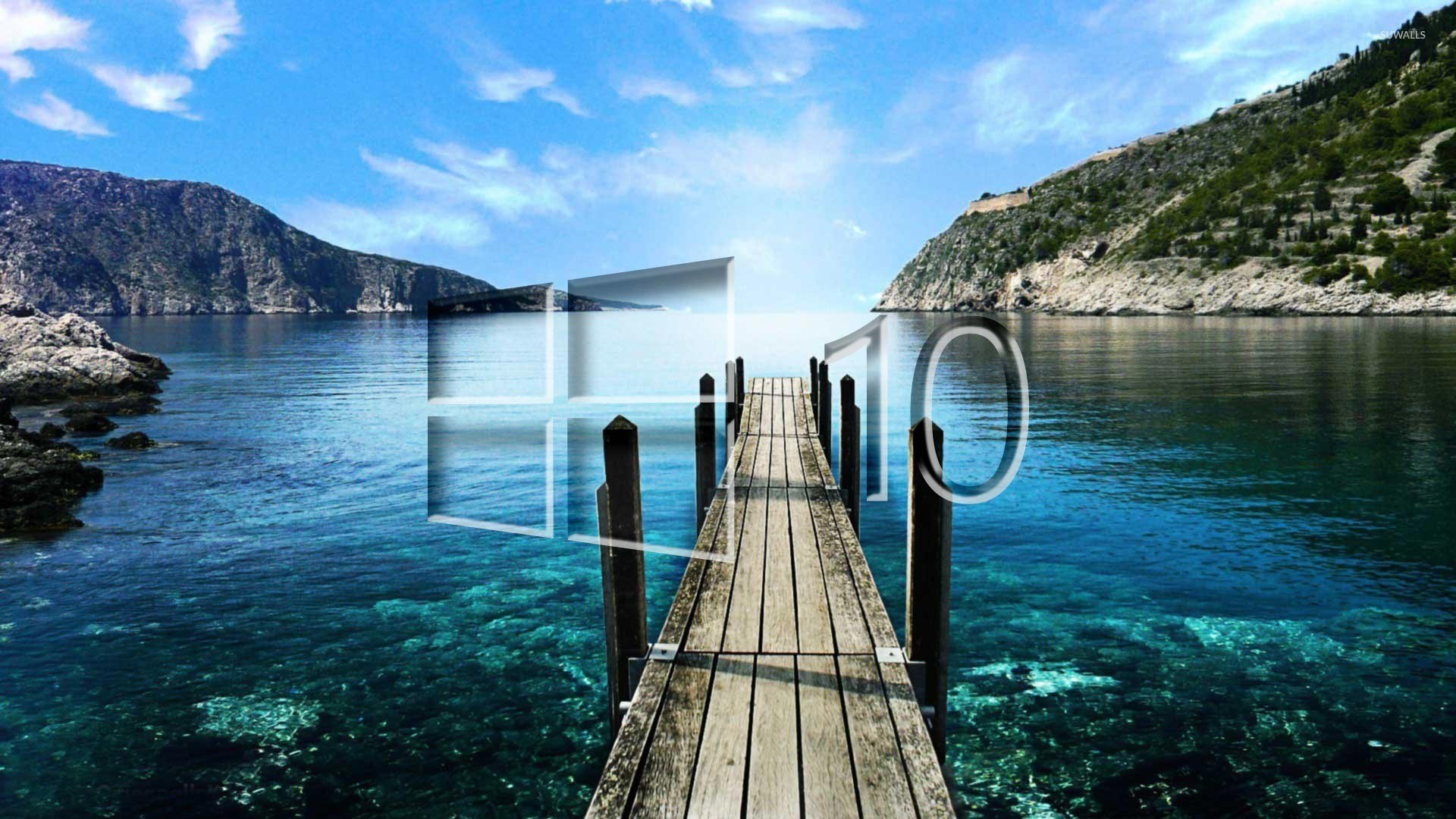 Windows 10 logo superimposed on a scenic image of a wooden pier extending into a tranquil turquoise bay, with clear water and rocky shores, nestled amidst verdant hills