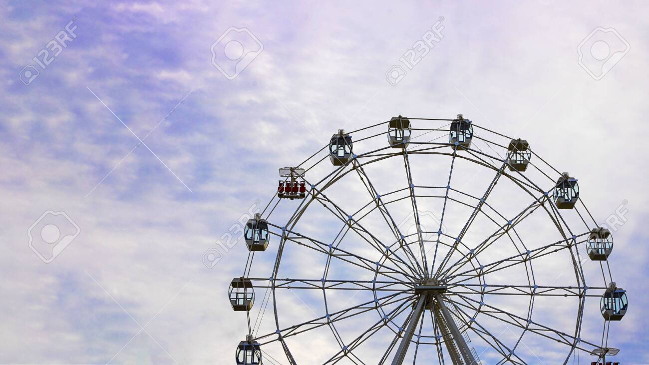Empty Observation Wheel On The Background Of Blue Sky With White
