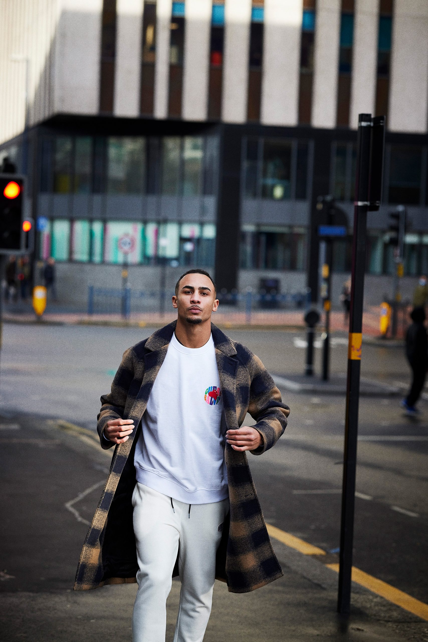 Boxer Benjamin Whittaker walks down a city street in a stylish plaid coat and white sweatpants