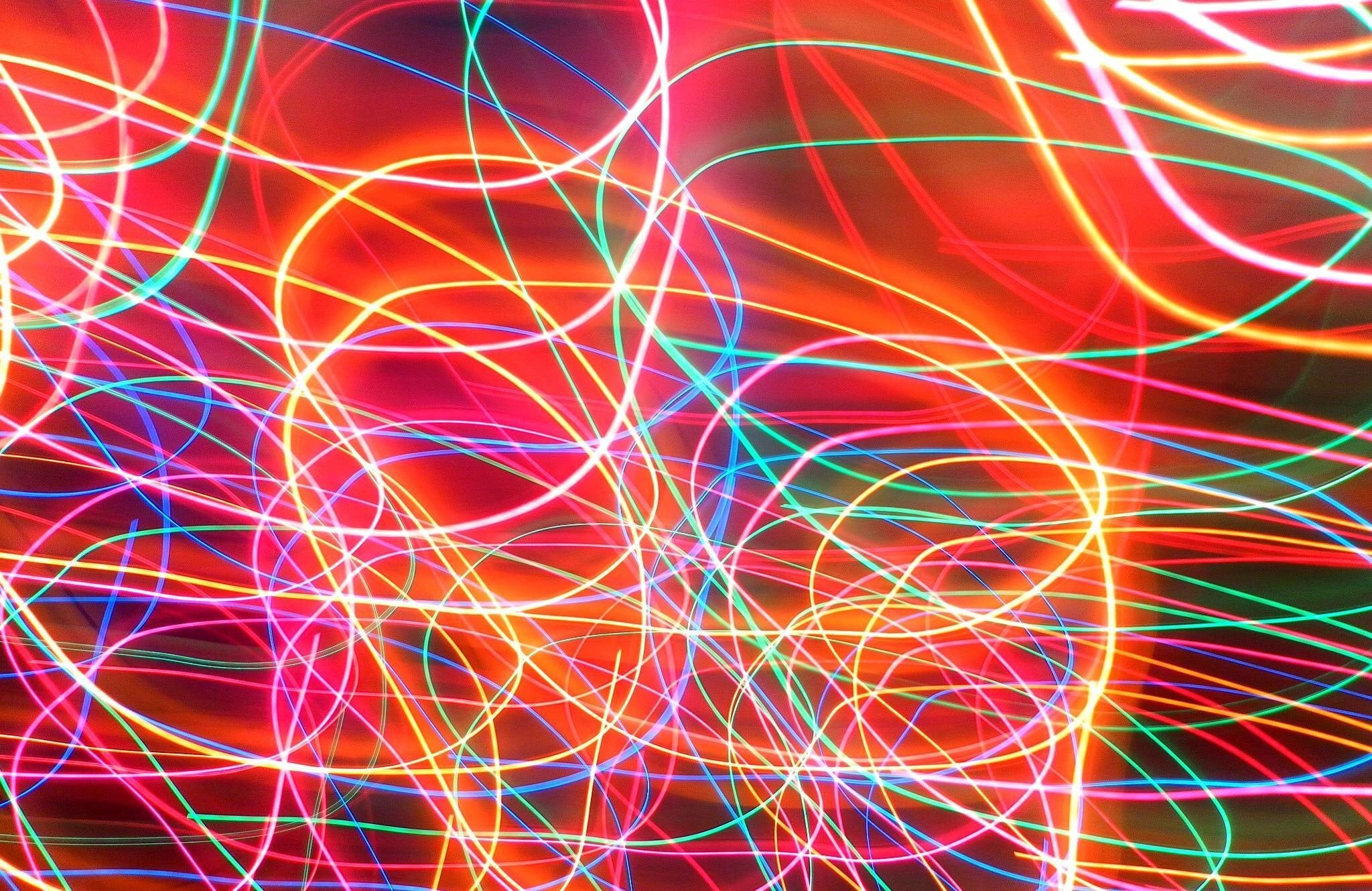 Abstract streaks of vibrant neon light in red, pink, green, and blue, creating a dynamic and energetic wallpaper