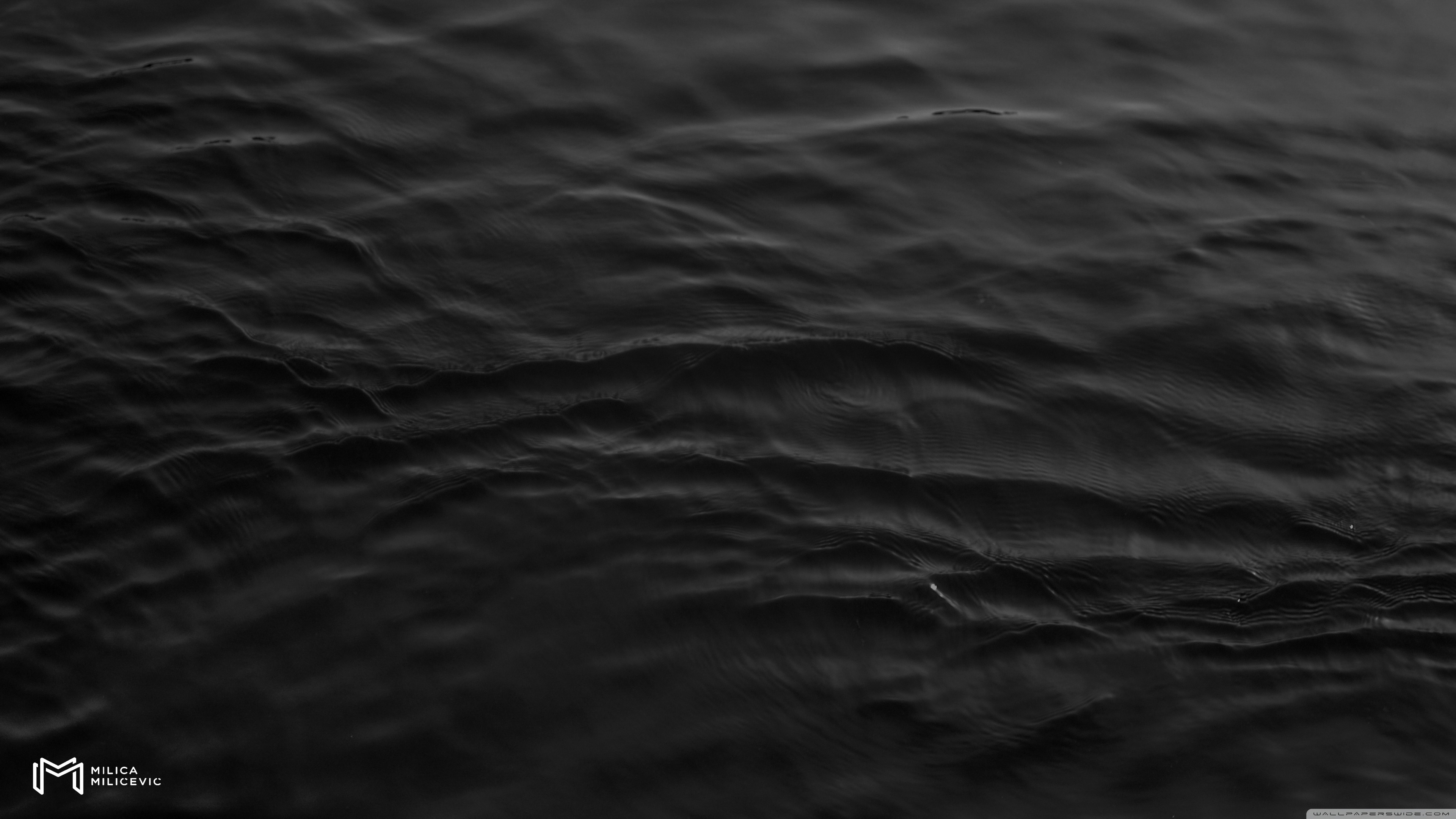 Dark and rippling black water surface background in 4k resolution