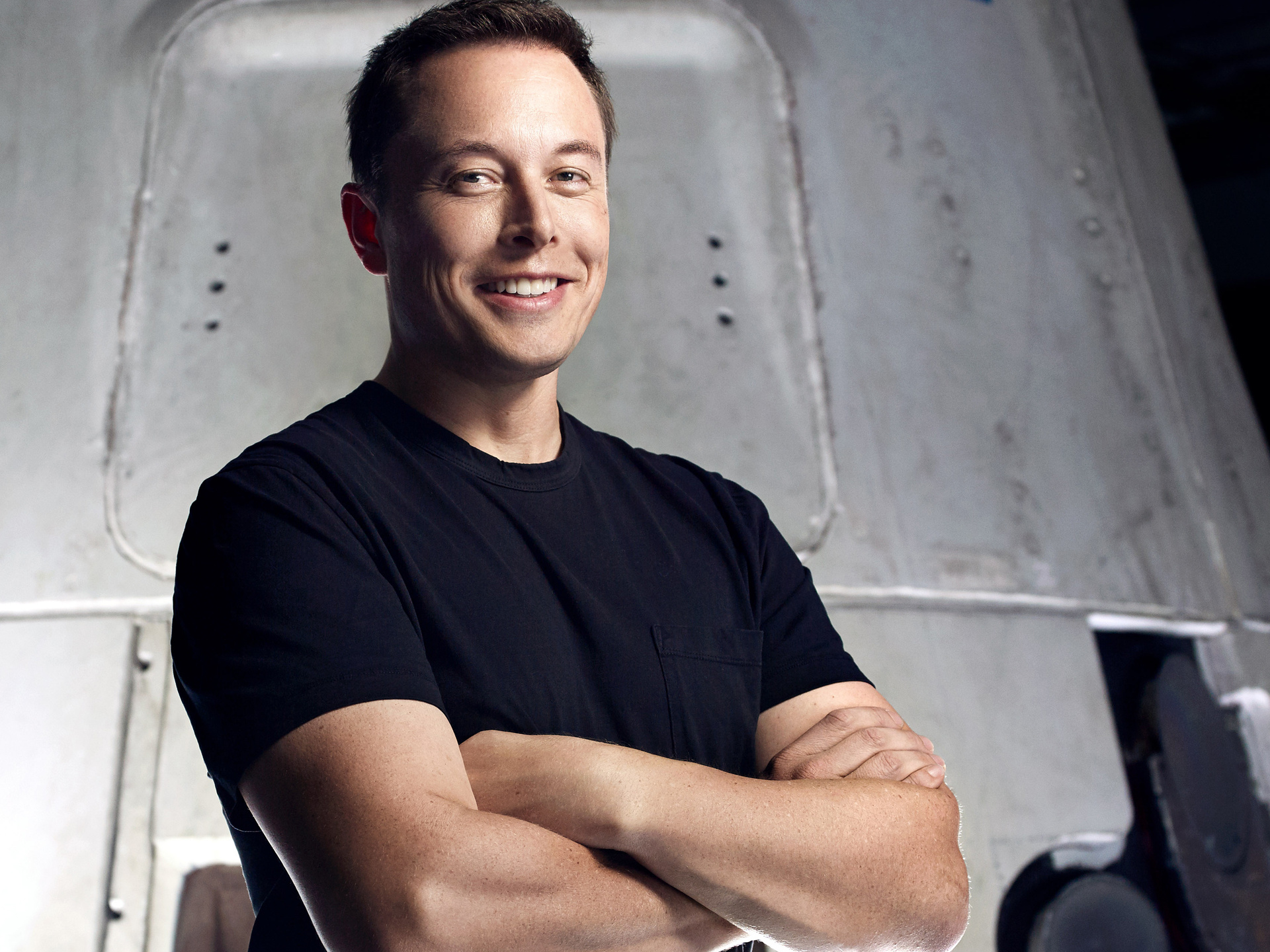 Elon Musk, CEO of SpaceX and Tesla, stands with his arms crossed in front of a spacecraft, exuding confidence and vision