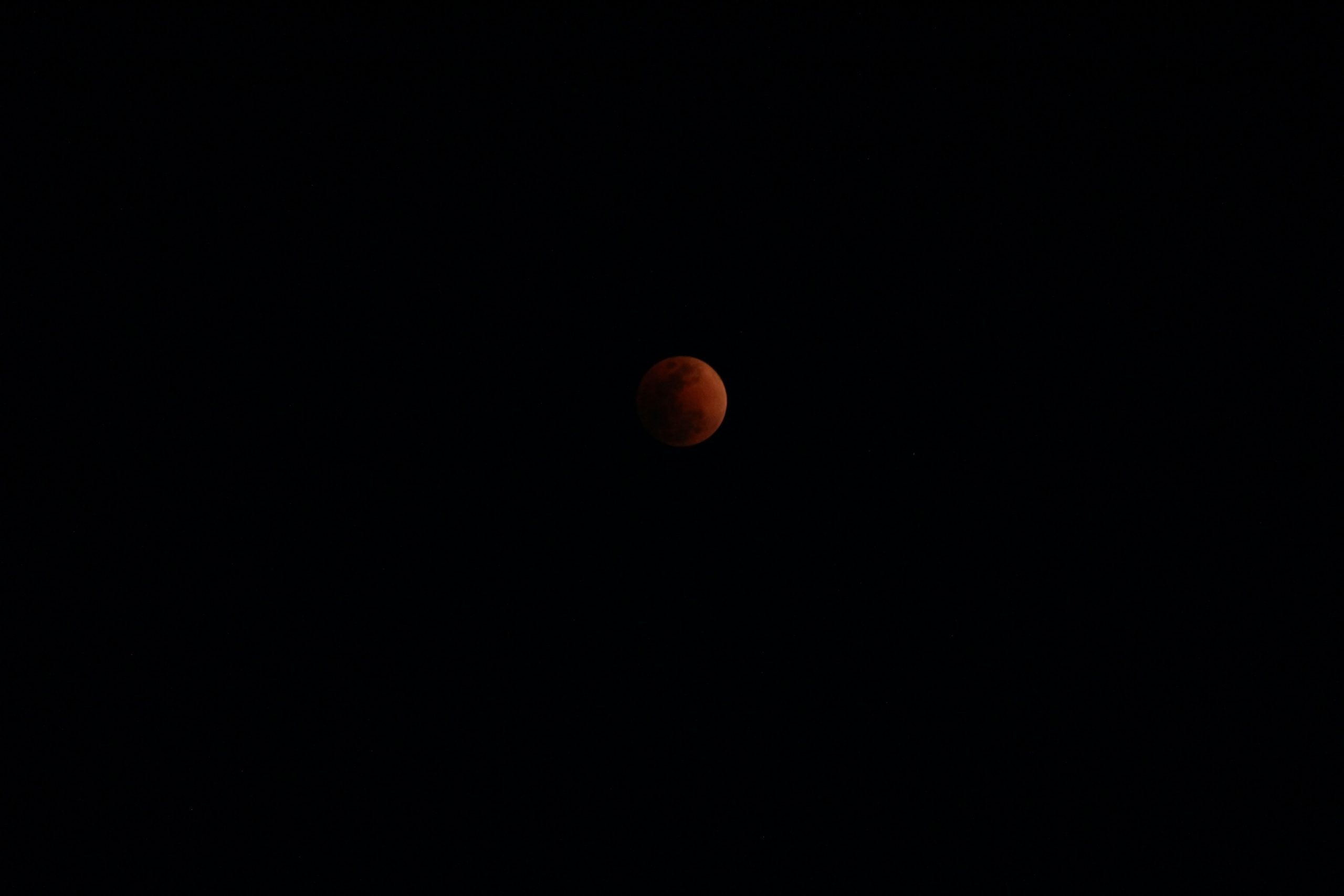 A dark, captivating image of a partially eclipsed blood moon against a black sky, perfect for a 4K wallpaper